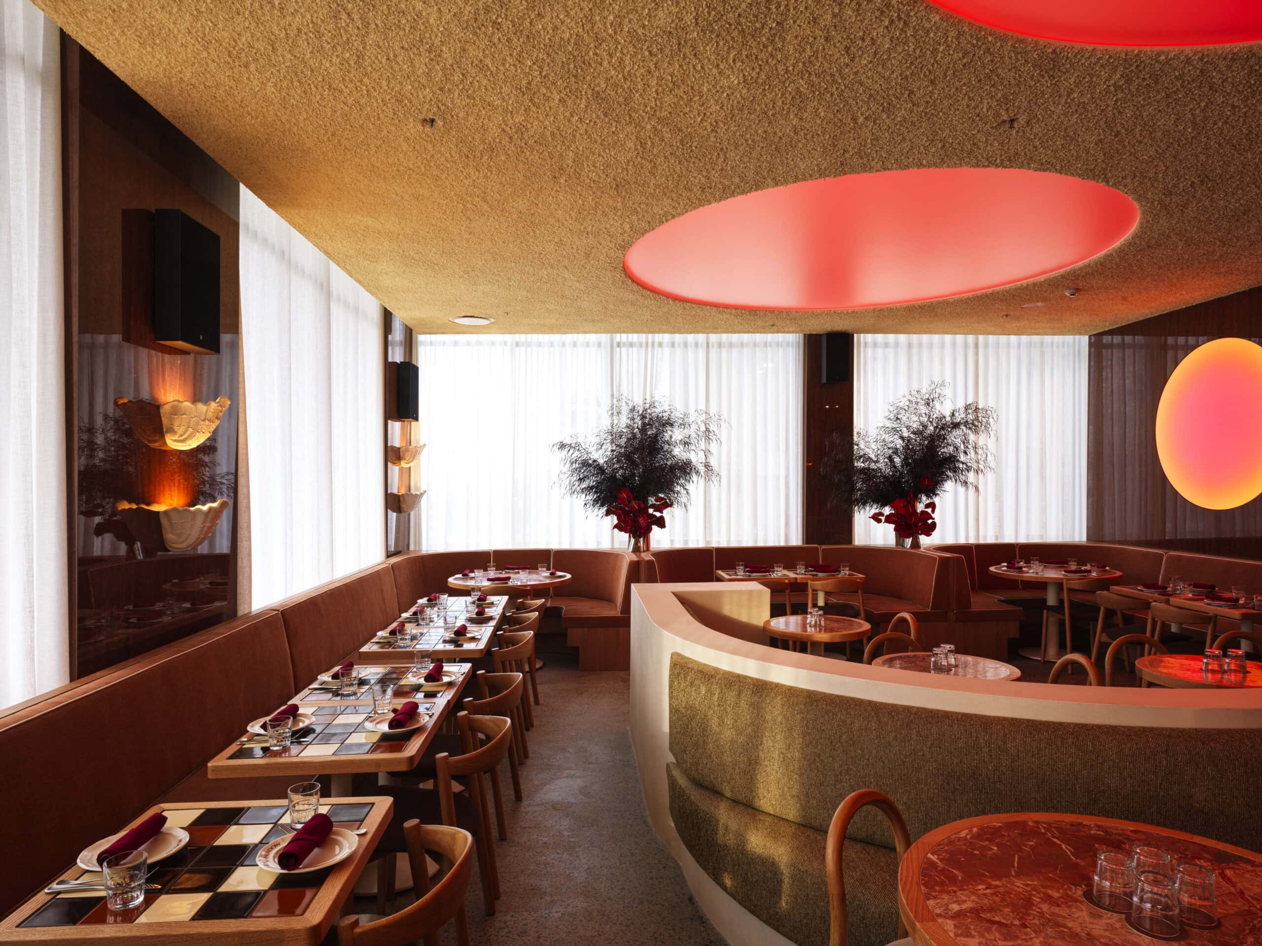 Dining room interior with curved velvet booths red oval ceiling lights and marble tables at Meadow Cronulla Sydney