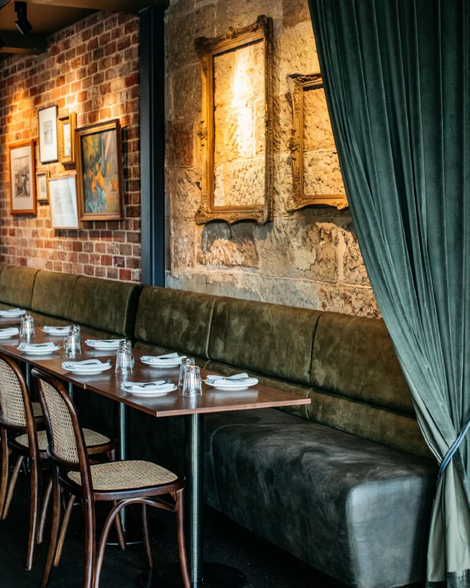 The dining room at mille vin in surry hills featuring an exposed brick wall and velvet banquettes.