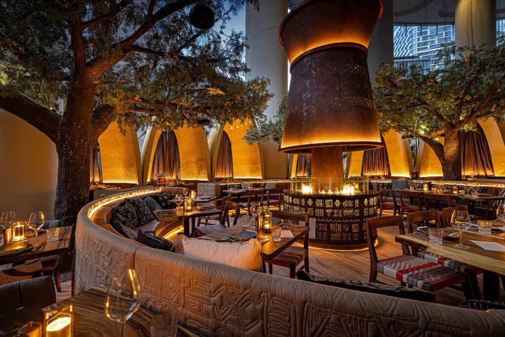 Dining room with central fire pit and acacia trees at The Meat and Wine Co Circular Quay Sydney
