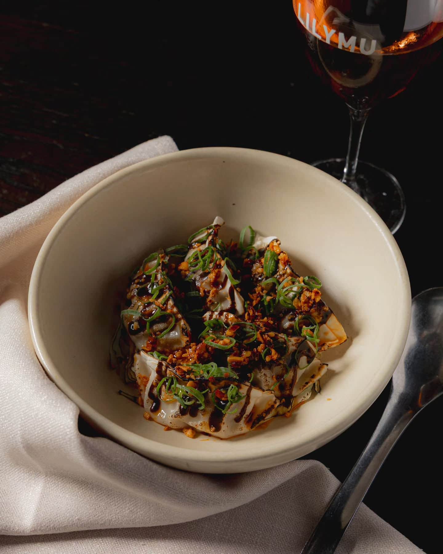 A bowl or dumplings and a glass of white wine at Lilu Mu in Parramatta.