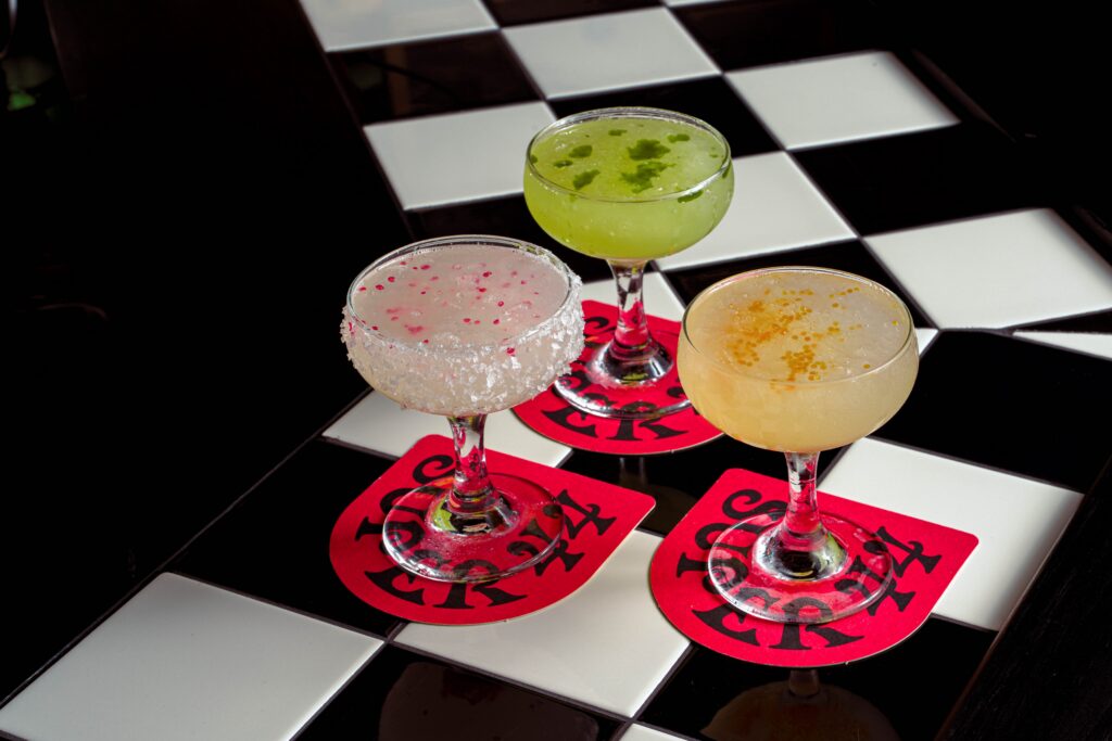 Three colourful margaritas on checkerboard tiles at Super 44 margarita bar Newtown Sydney