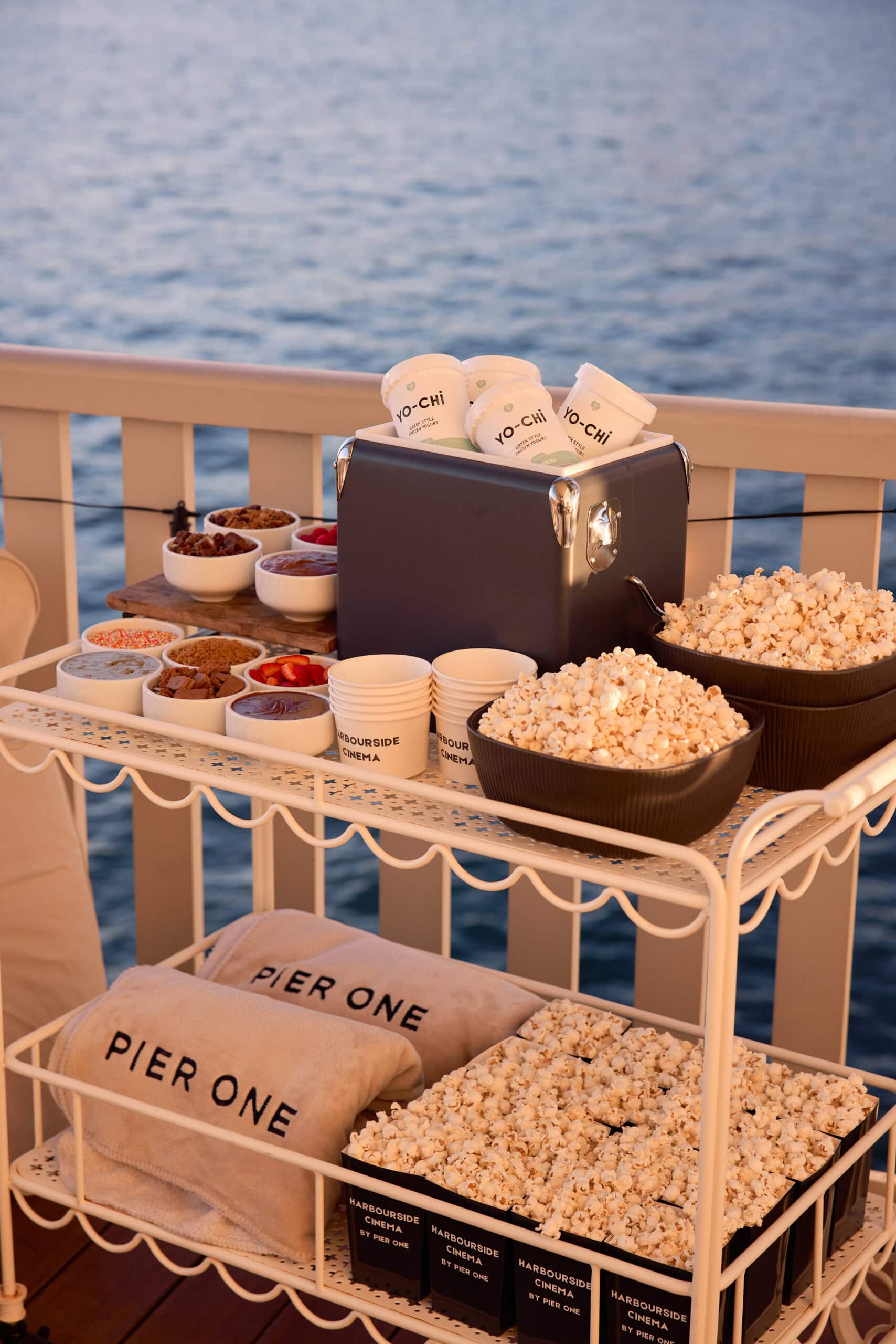 Harbourside Cinema popcorn Yo-Chi frozen yoghurt toppings bar and Pier One branded blankets on trolley overlooking the harbour at Pier One Walsh Bay Sydney