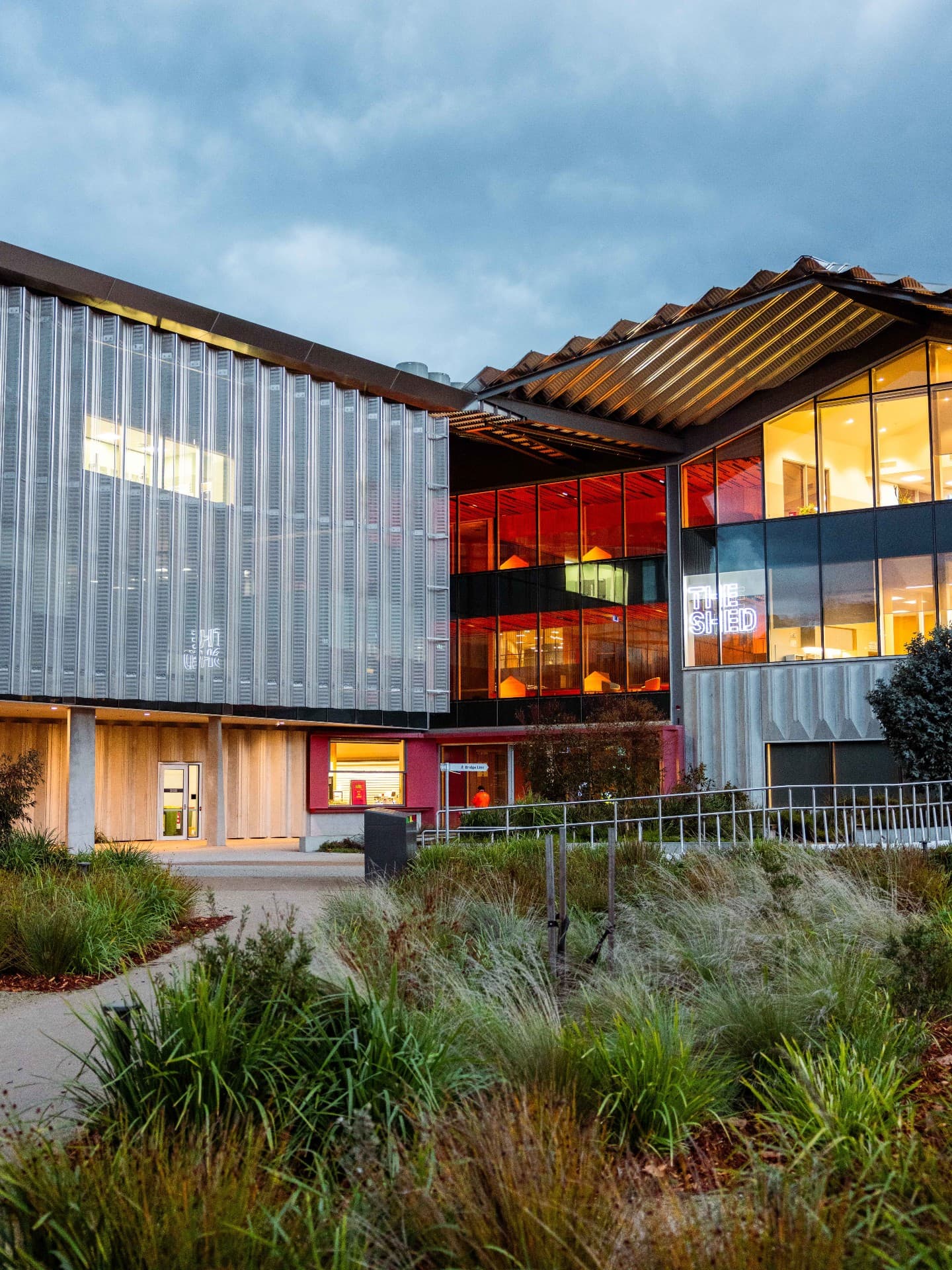 The Shed in Launceston, home to Kudos by Parla, photographed at dusk with landscaped gardens in the foreground.