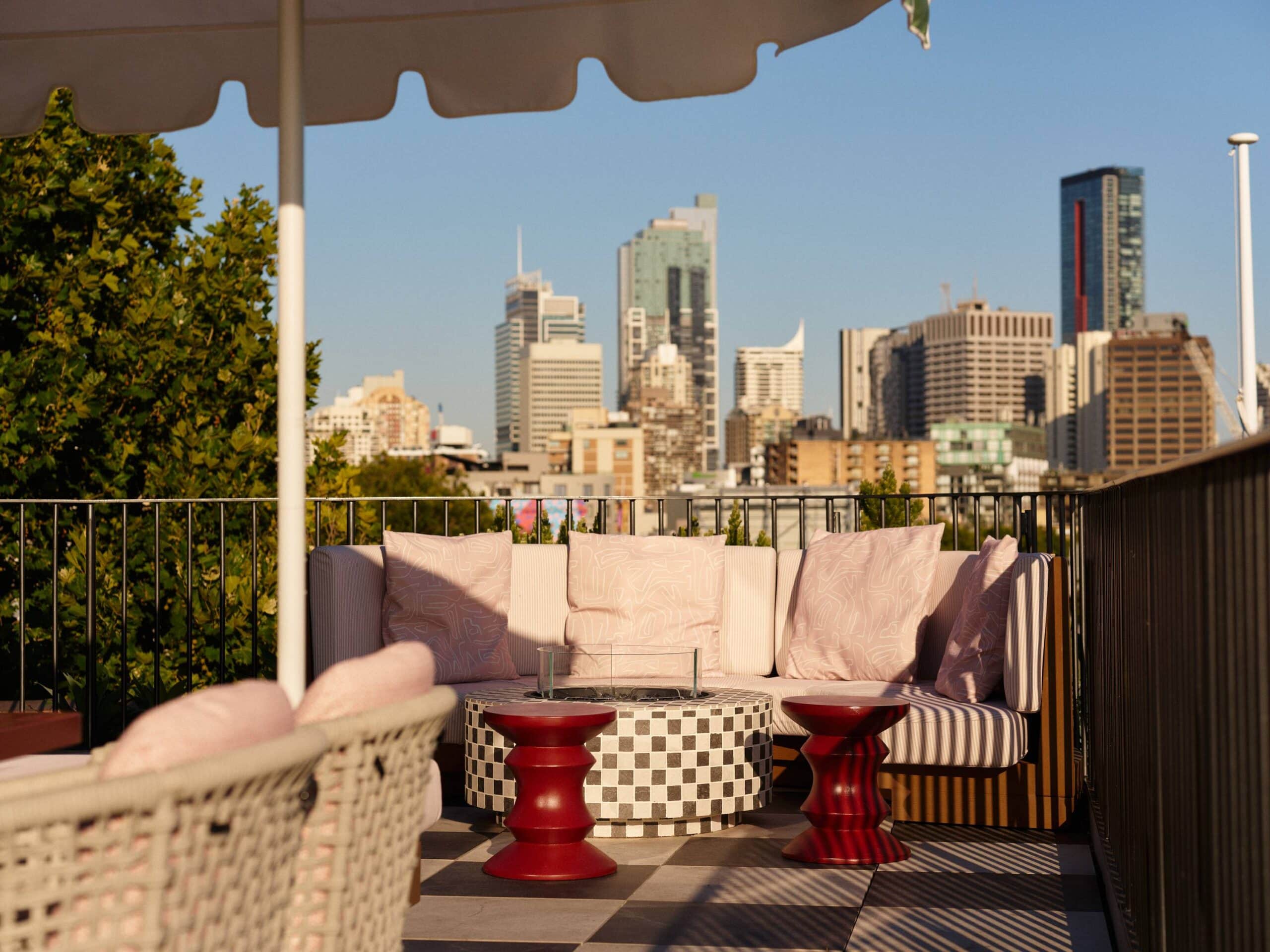 Rooftop terrace with pink cushioned seating checkered coffee table and Sydney city skyline view Monica's Paddington Sydney