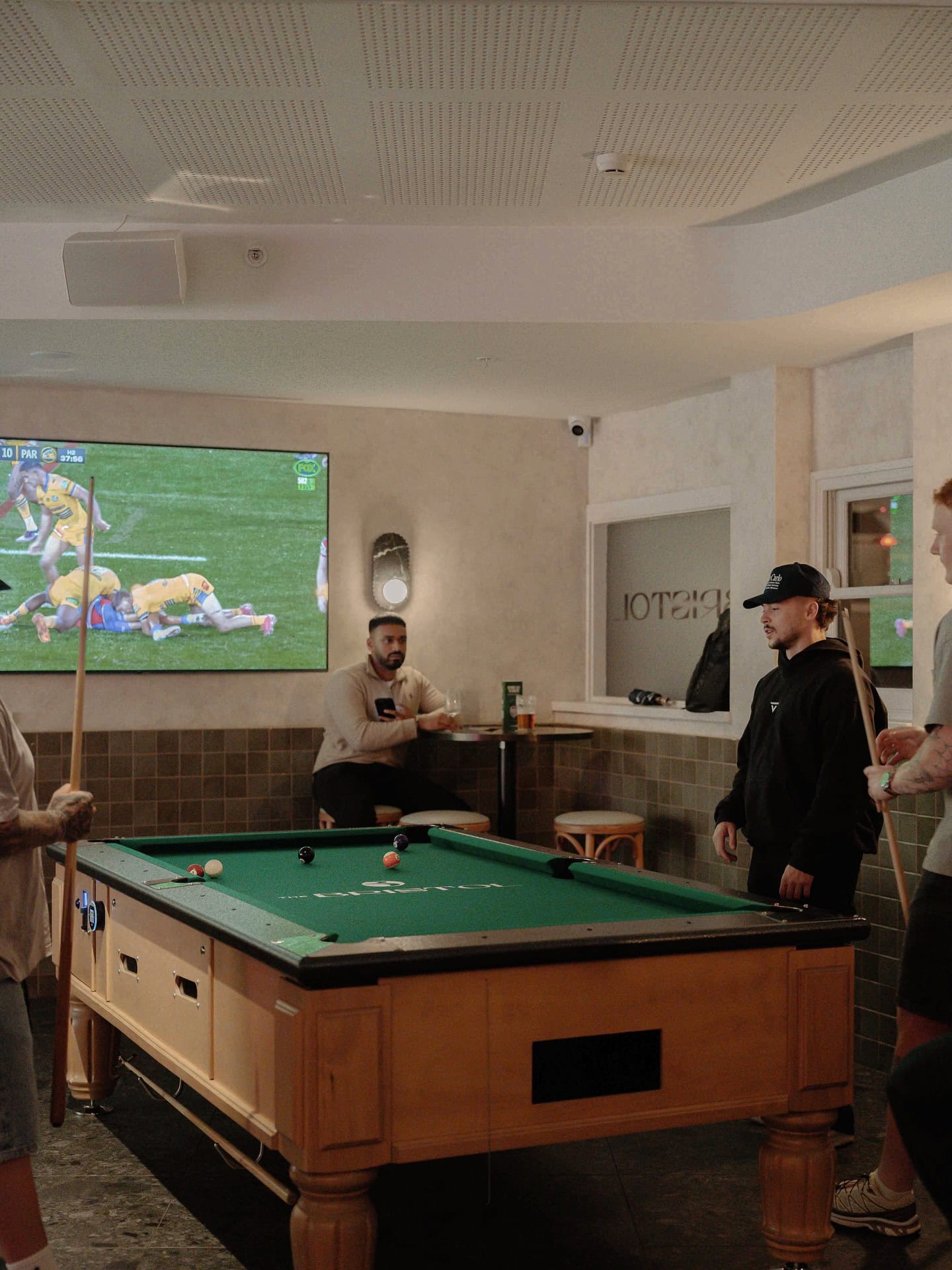 People playing pool in front of live sport on the television at the bristol in sydney