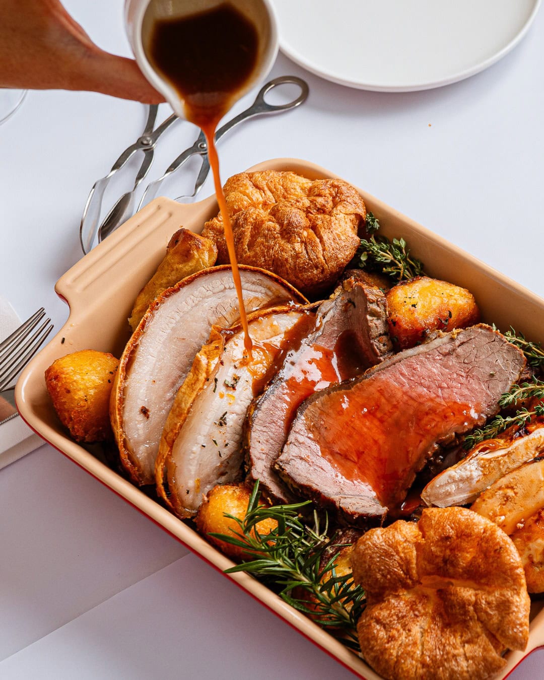 Someone pouring gravy over a full roast dinner in a roasting tray at the lord nelson brewery in the rocks.