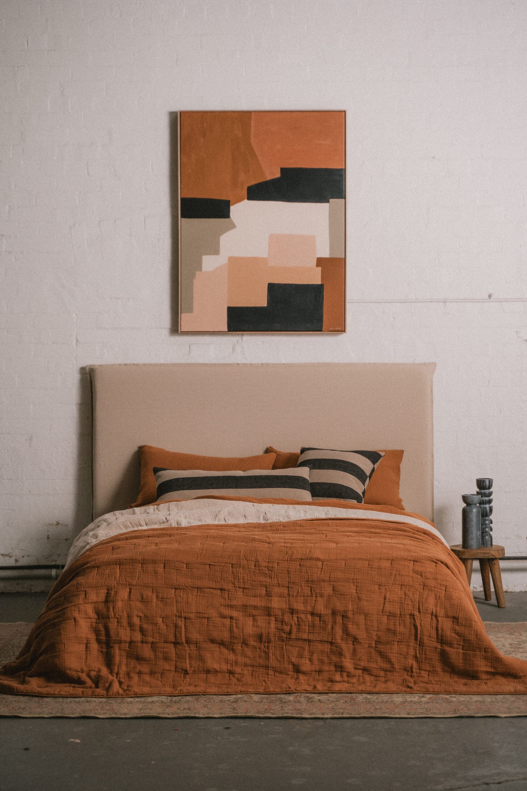 Terracotta linen bedding with striped cushions and abstract artwork above bed styled by Saarde archive sale Paddington Sydney