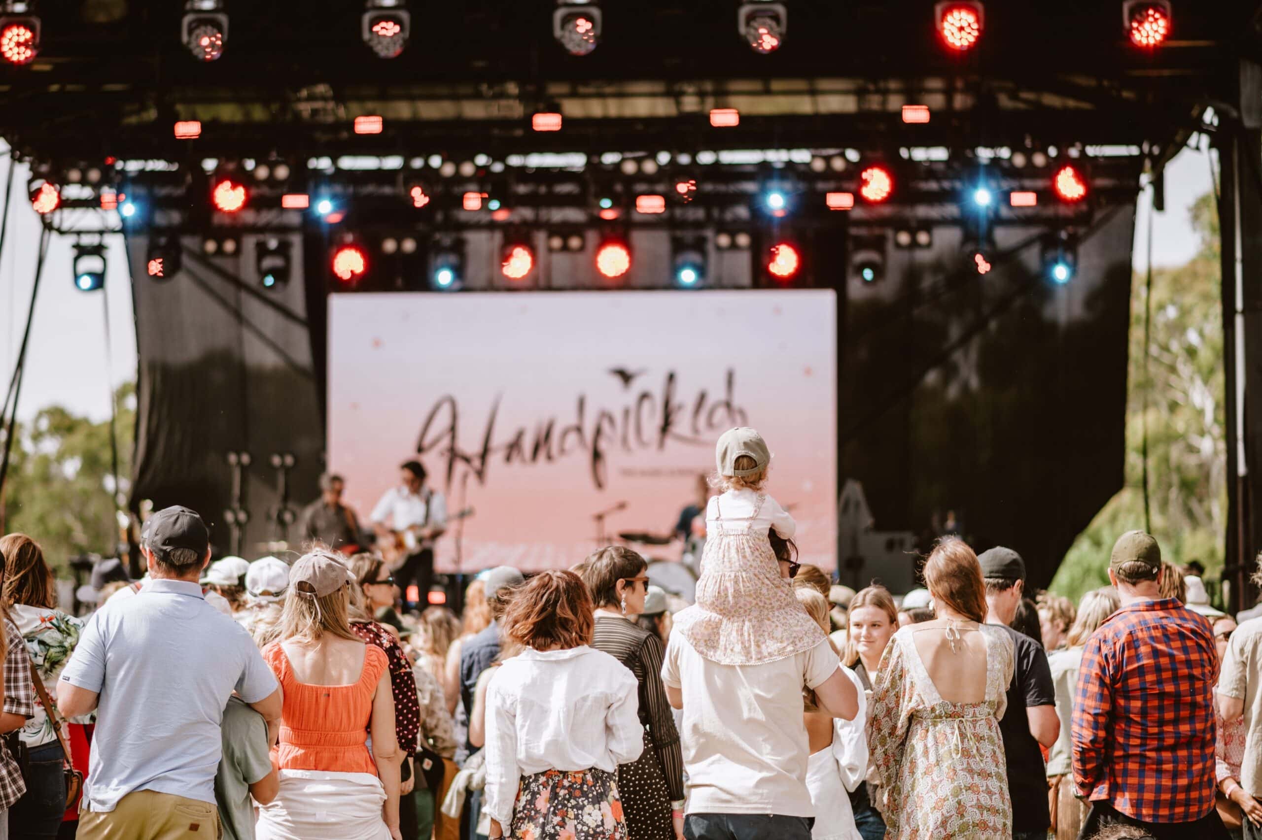Crowds gathered in front of the main stage at Handpicked Festival, enjoying live music in a relaxed outdoor setting among the trees.