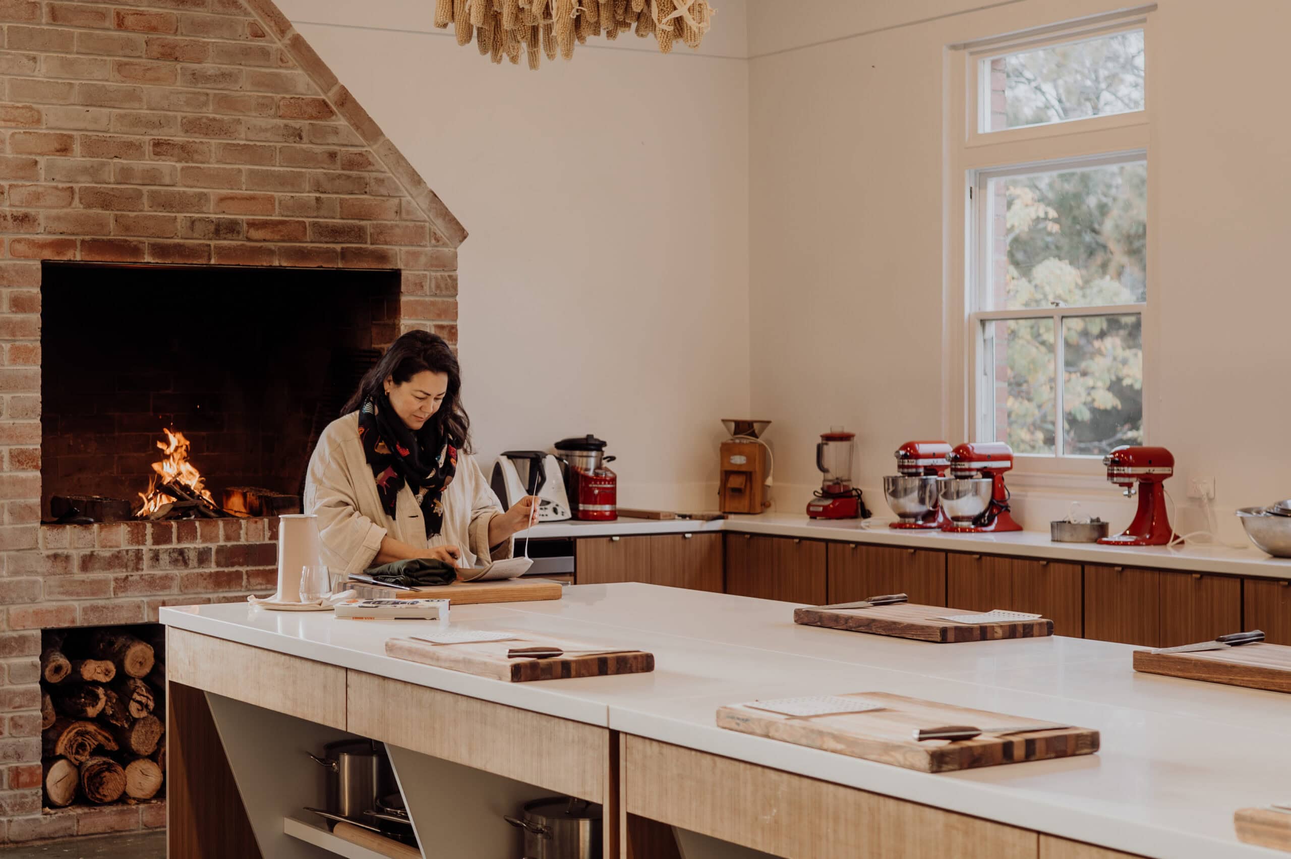 Emiko Davies, a guest cooking teacher preparing notes beside the open fireplace at The Agrarian Kitchen cooking school.