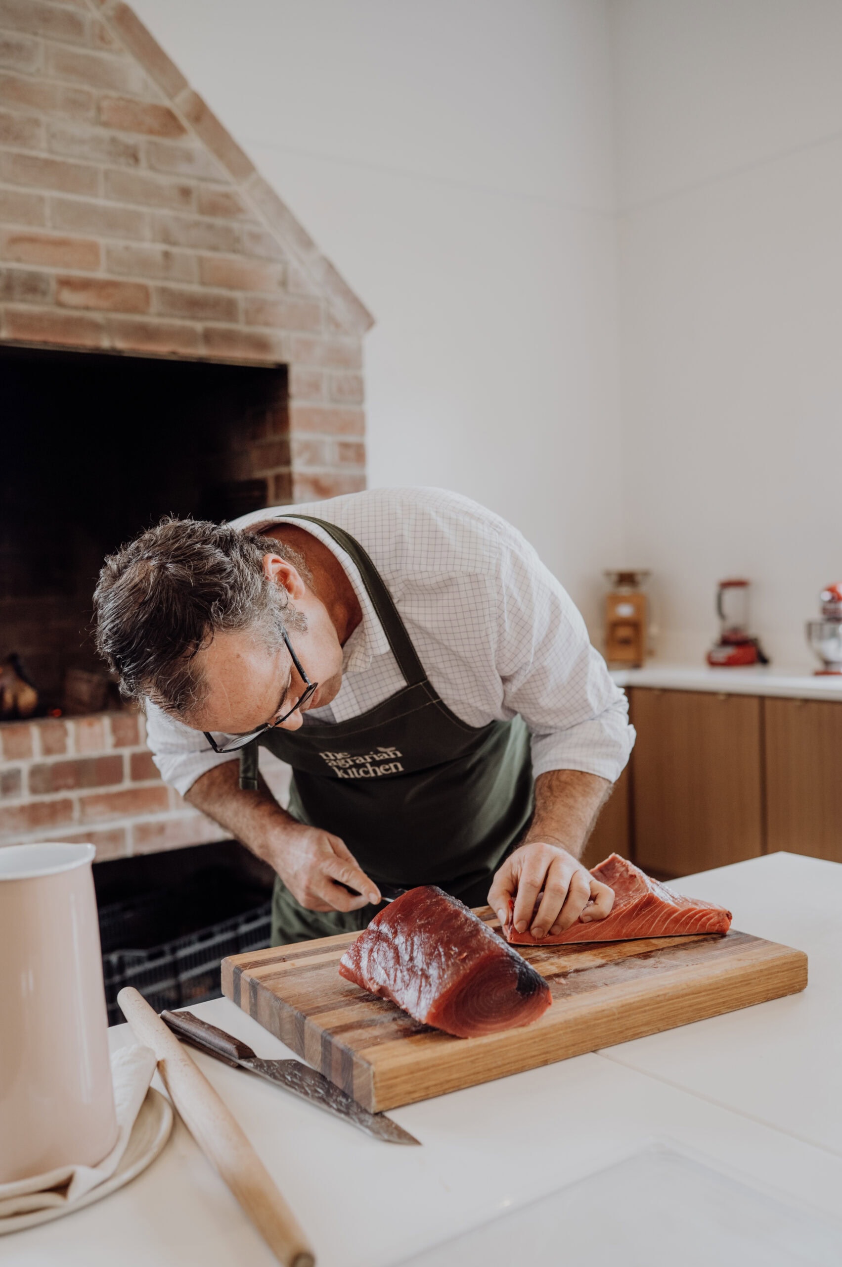 A chef slicing fresh fish during a cooking class inside The Agrarian Kitchen teaching kitchen.