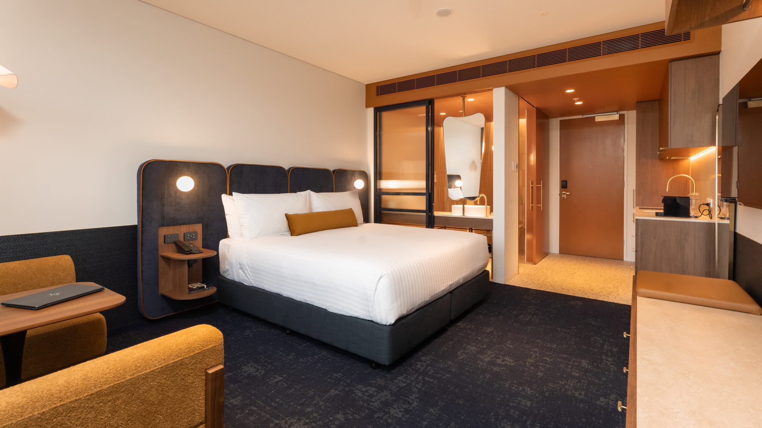 A contemporary hotel room at Hotel Panorama featuring a king bed, warm timber tones and an ensuite.