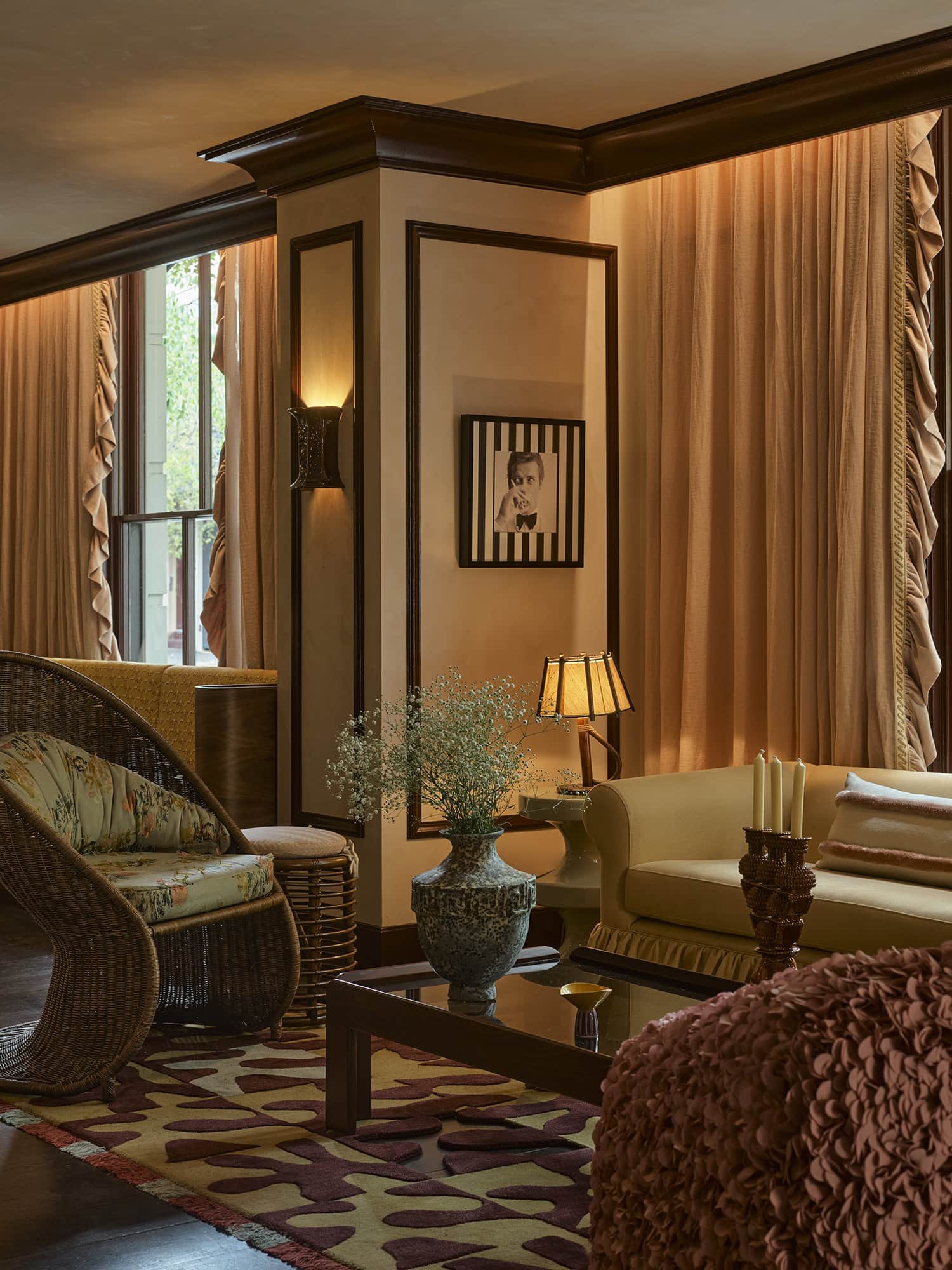 Moody lounge interior with wicker chair draped curtains and eclectic artwork at The James Sydney CBD