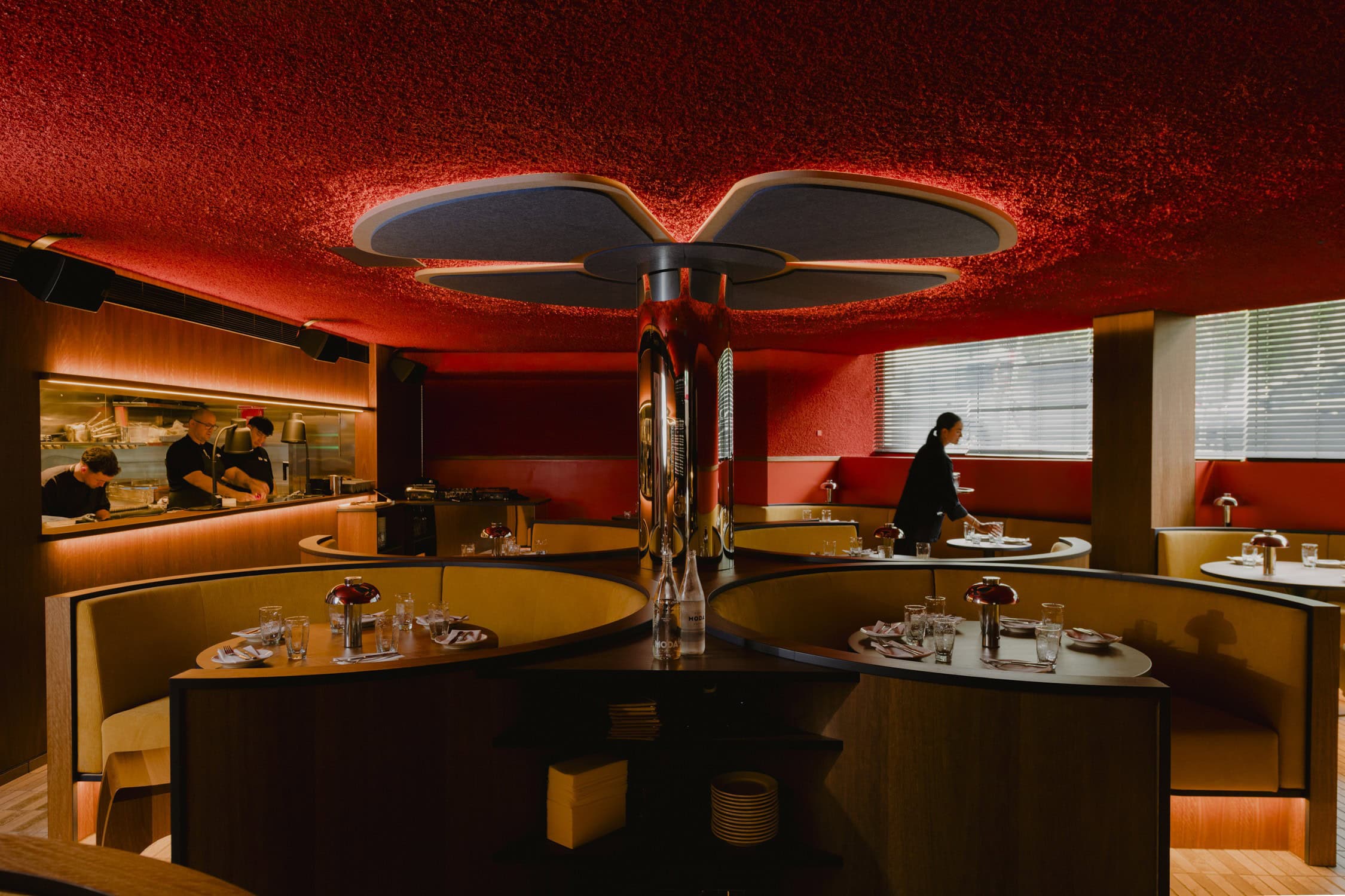 Besa restaurant interior with red textured ceiling curved gold booth seating and open kitchen Bondi Sydney