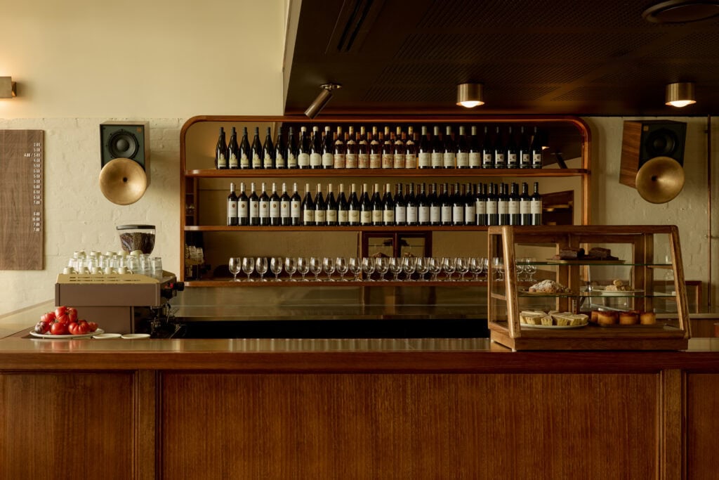 The oak bar at Bistro Tino with a series of wine bottles lined up behind it.