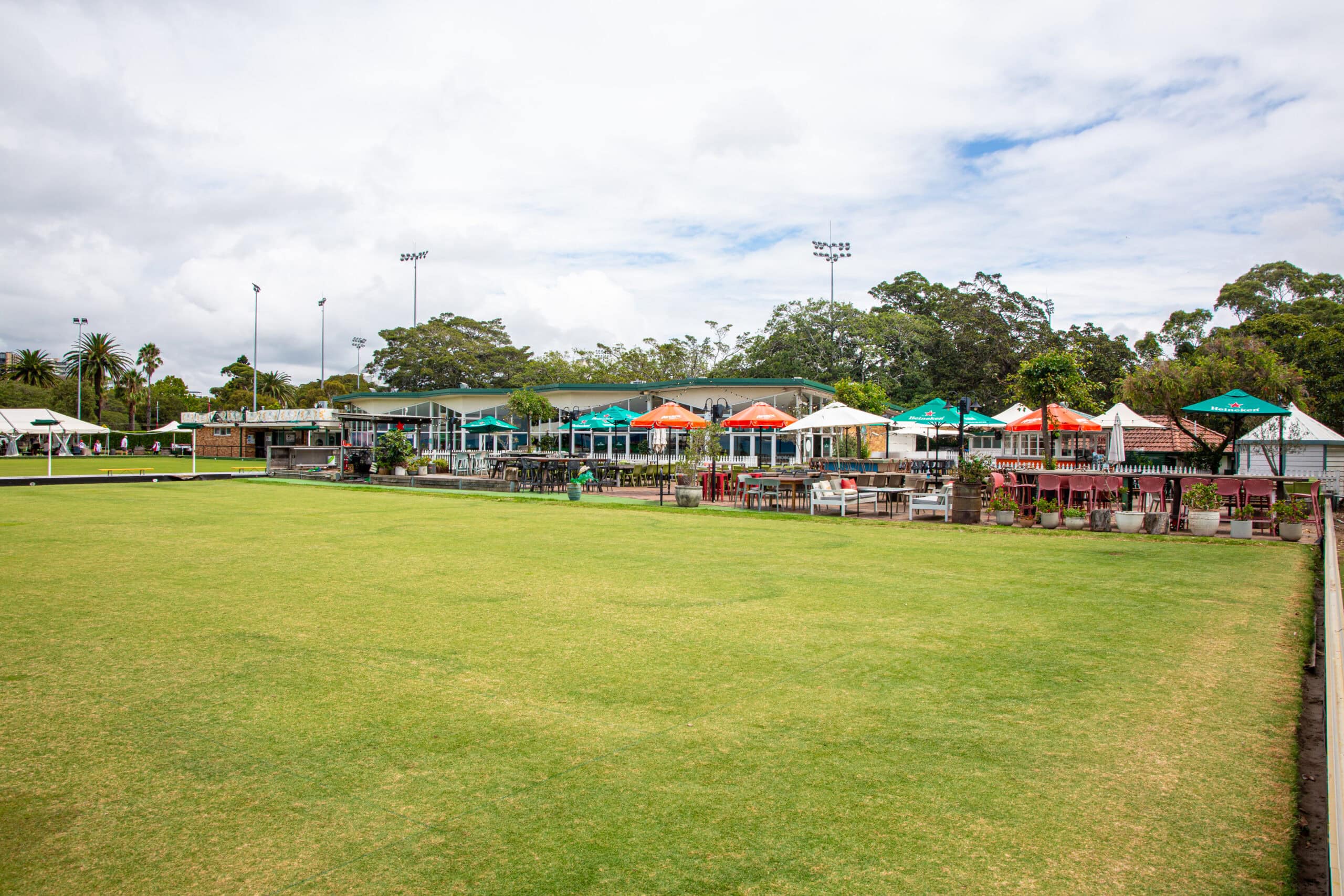 Bowling green with colourful outdoor terrace umbrellas and bar The Greens North Sydney