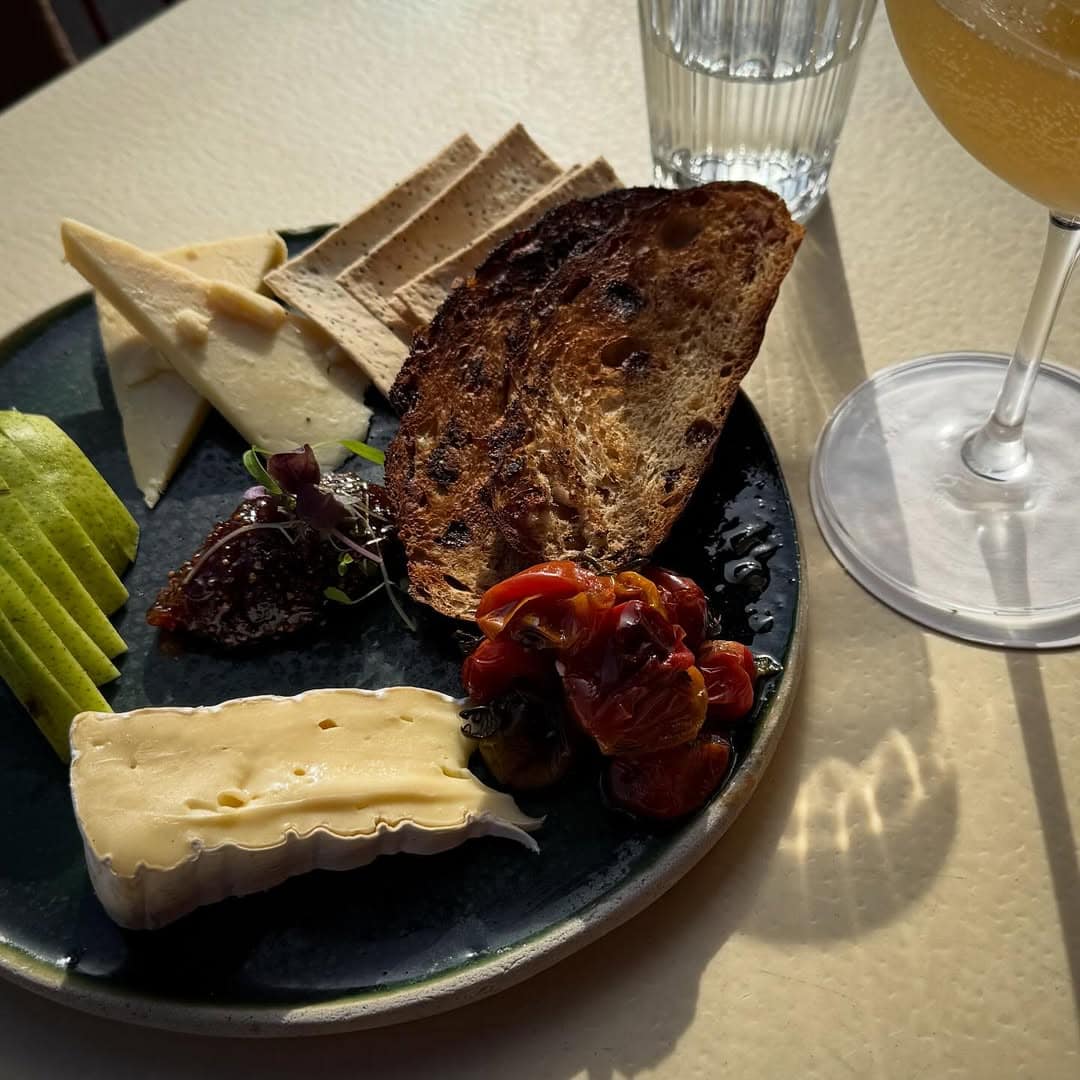 Cheese board with brie sourdough toast roasted tomatoes fig jam and apple with cocktail at The Shop & Wine Bar Bondi Sydney