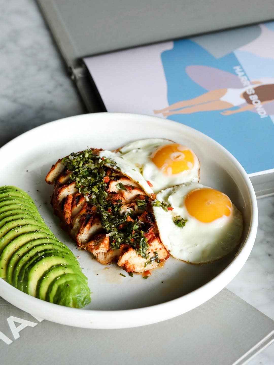 A chicken protein plate complete with sliced avocado and eggs at harrys in bondi.