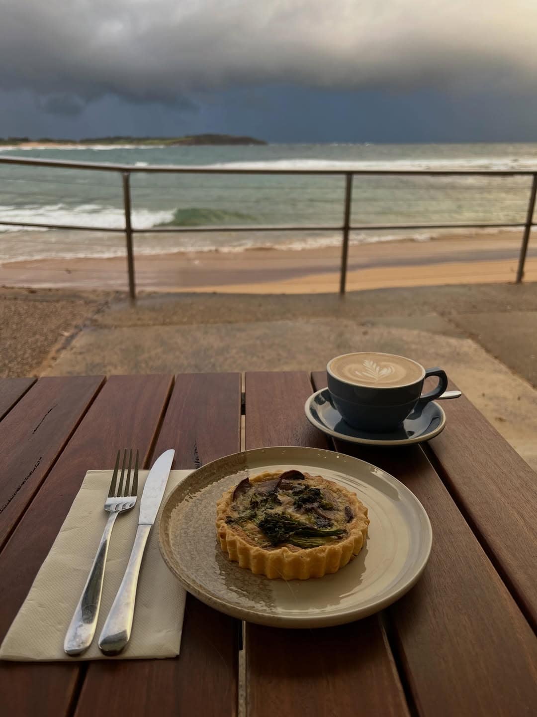 A coffee and tart atop a table overlooking the beach at gusto on the beach.