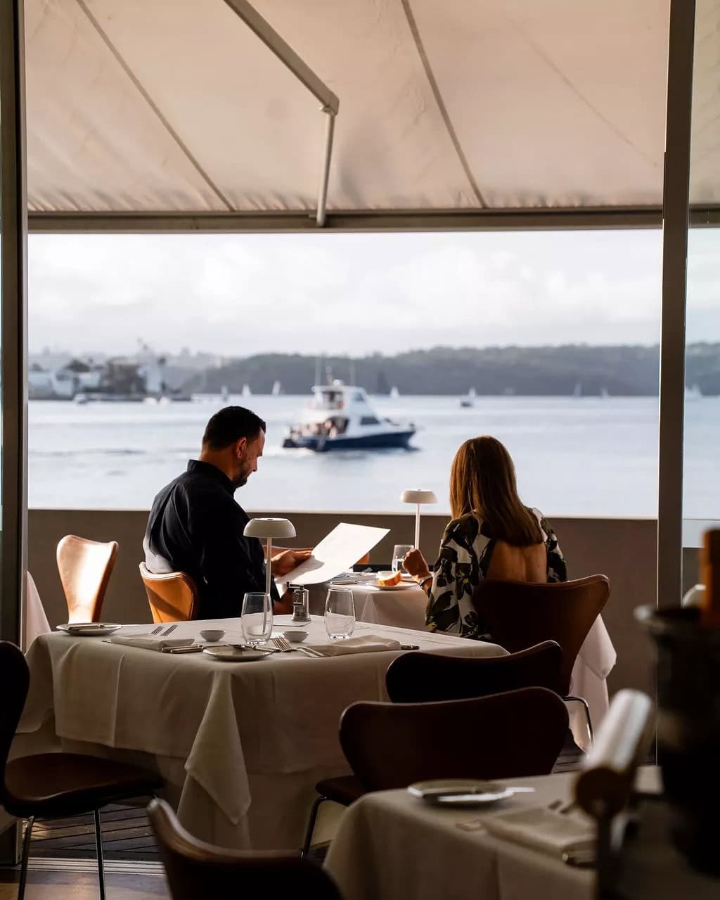 The silhouette of two people enjoying a meal and views at Catalina in Rose Bay.