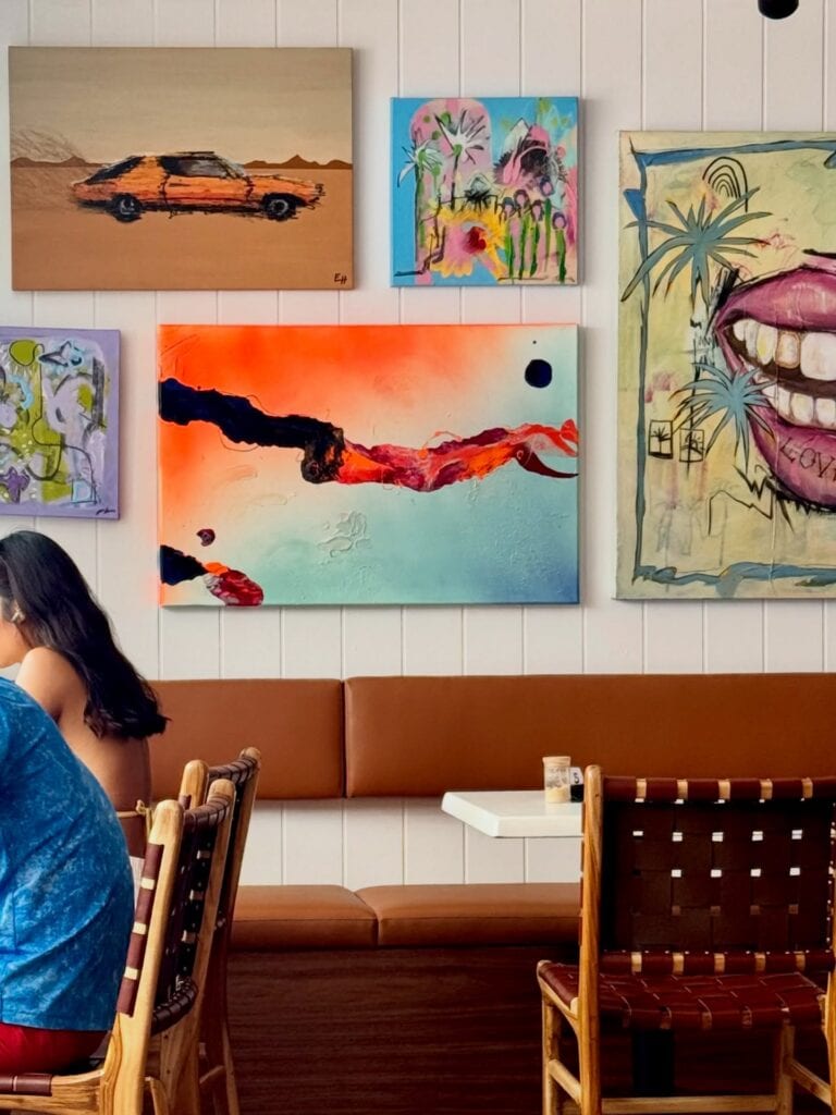 A part of the dining room at coop Bronte with pieces of colourful and unique art on the walls. 