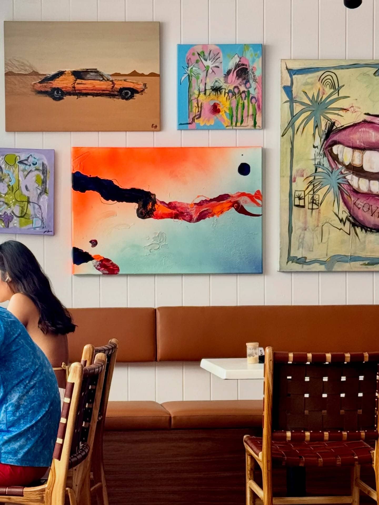 A part of the dining room at coop Bronte with pieces of colourful and unique art on the walls.