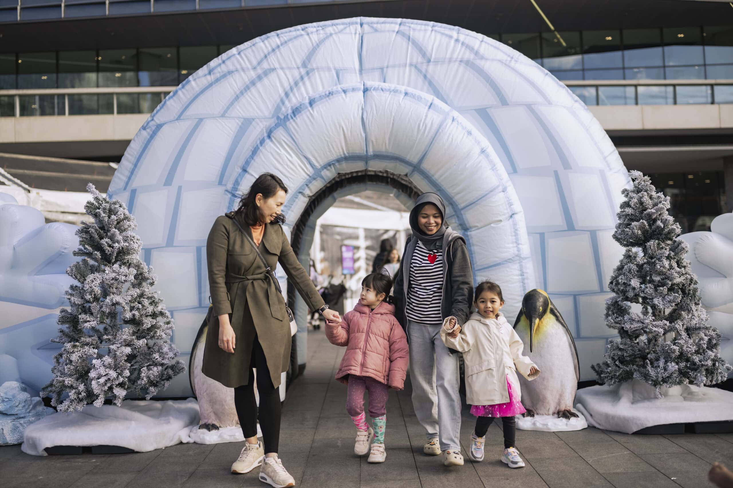 Families walking through inflatable igloo with penguin sculptures at Arctic Activity Zone winter school holidays Darling Harbour Sydney