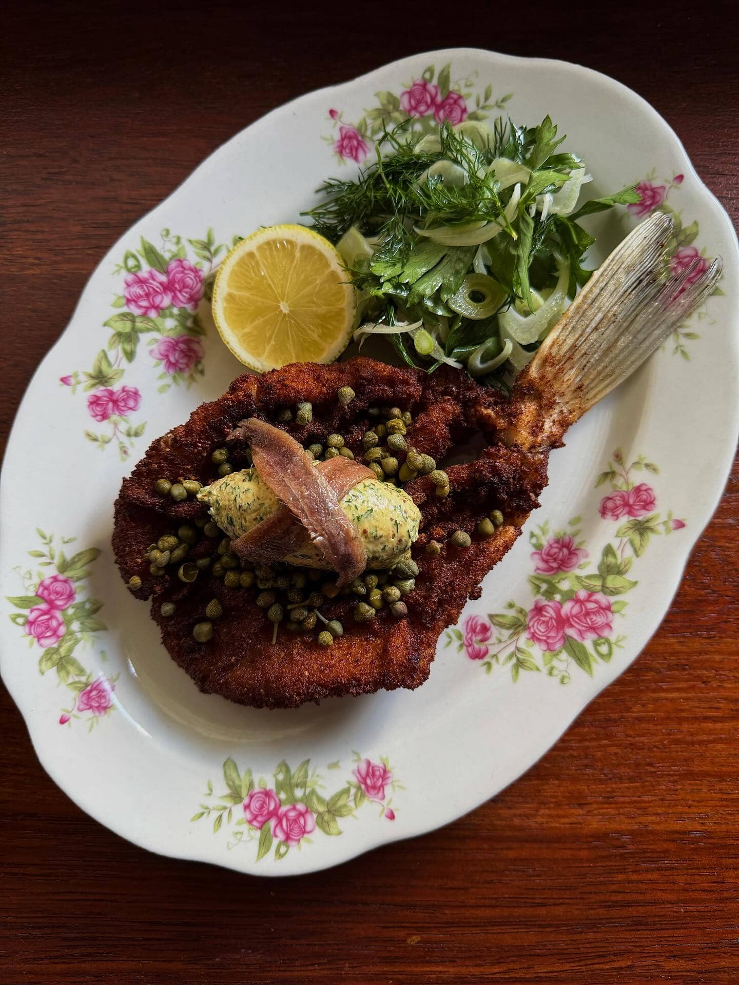 A fish schnitzel atop a floral oval plate at Bar Francine in Brisbane.