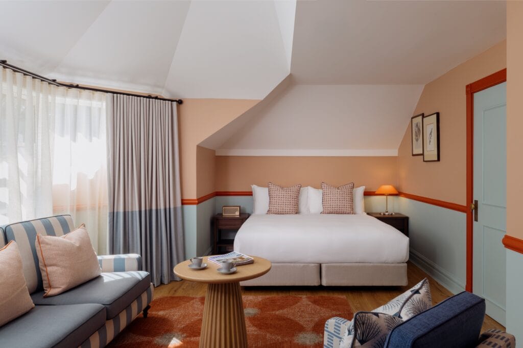 Redesigned guest room with peach walls king bed and striped sofa at Ardour Lilianfels Katoomba Blue Mountains
