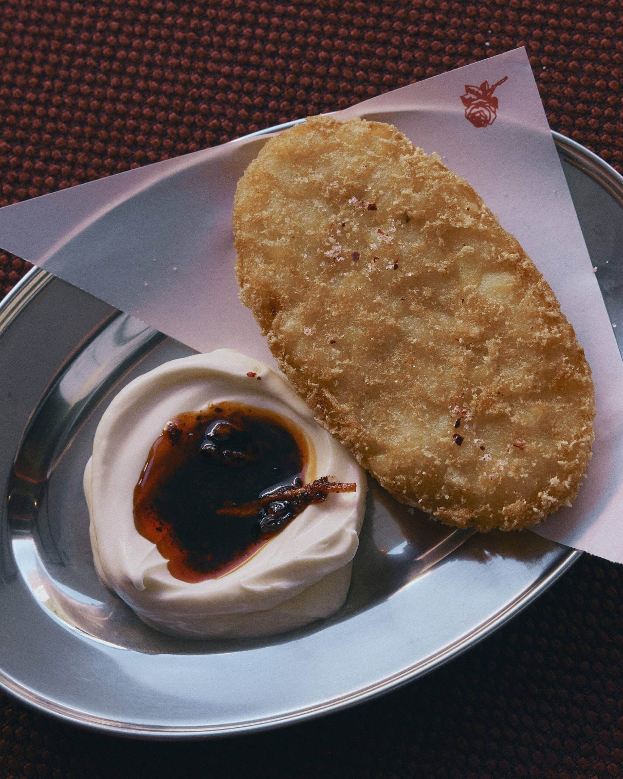 Crispy hash brown with whipped mayo and chilli oil on silver plate Ca Phe Mai Double Bay Sydney