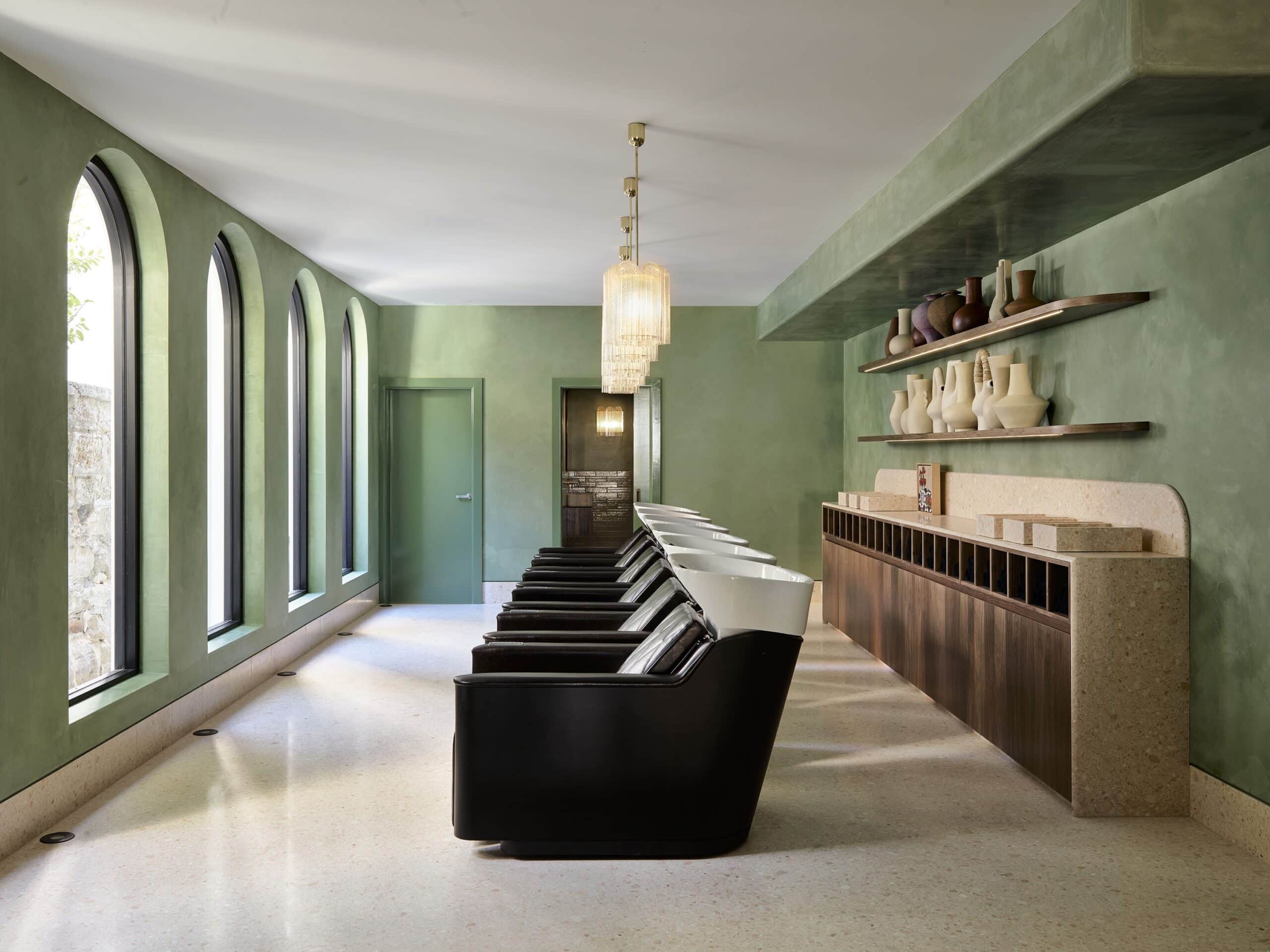 Headcase Hair wash basin room with row of black basins green plaster walls arched windows and glass chandelier Sydney