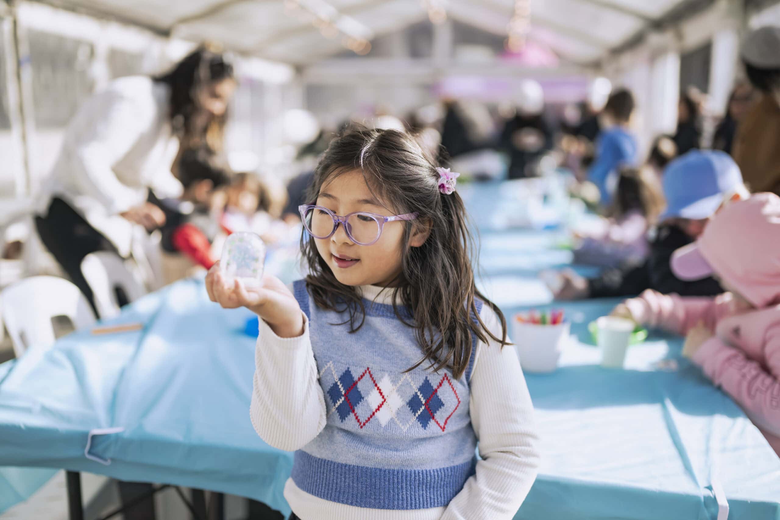 Child making a snow globe at kids craft activity during Arctic Activity Zone winter school holidays Darling Harbour Sydney