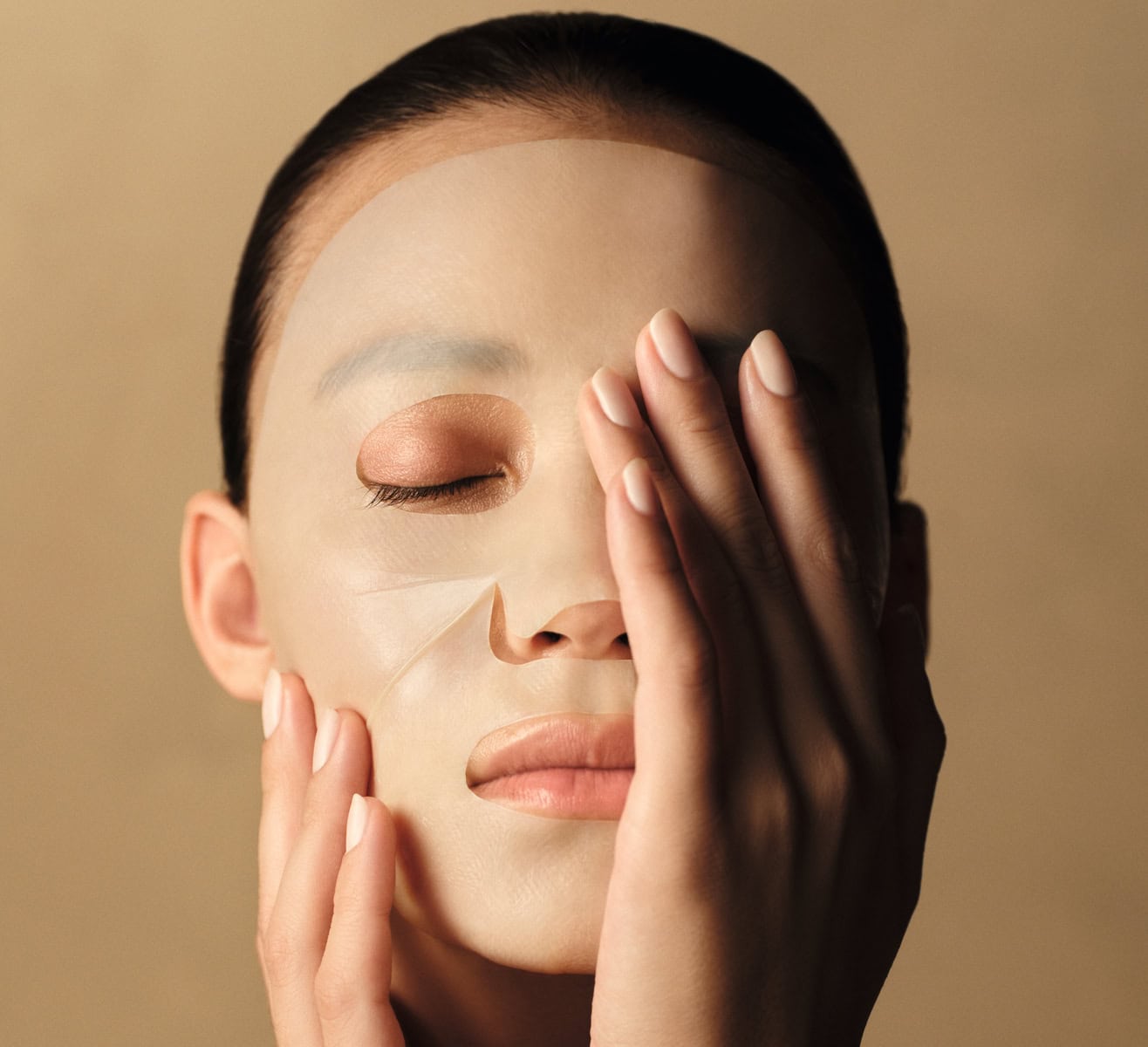 Model applying L'Occitane Immortelle Reset overnight serum sheet mask
