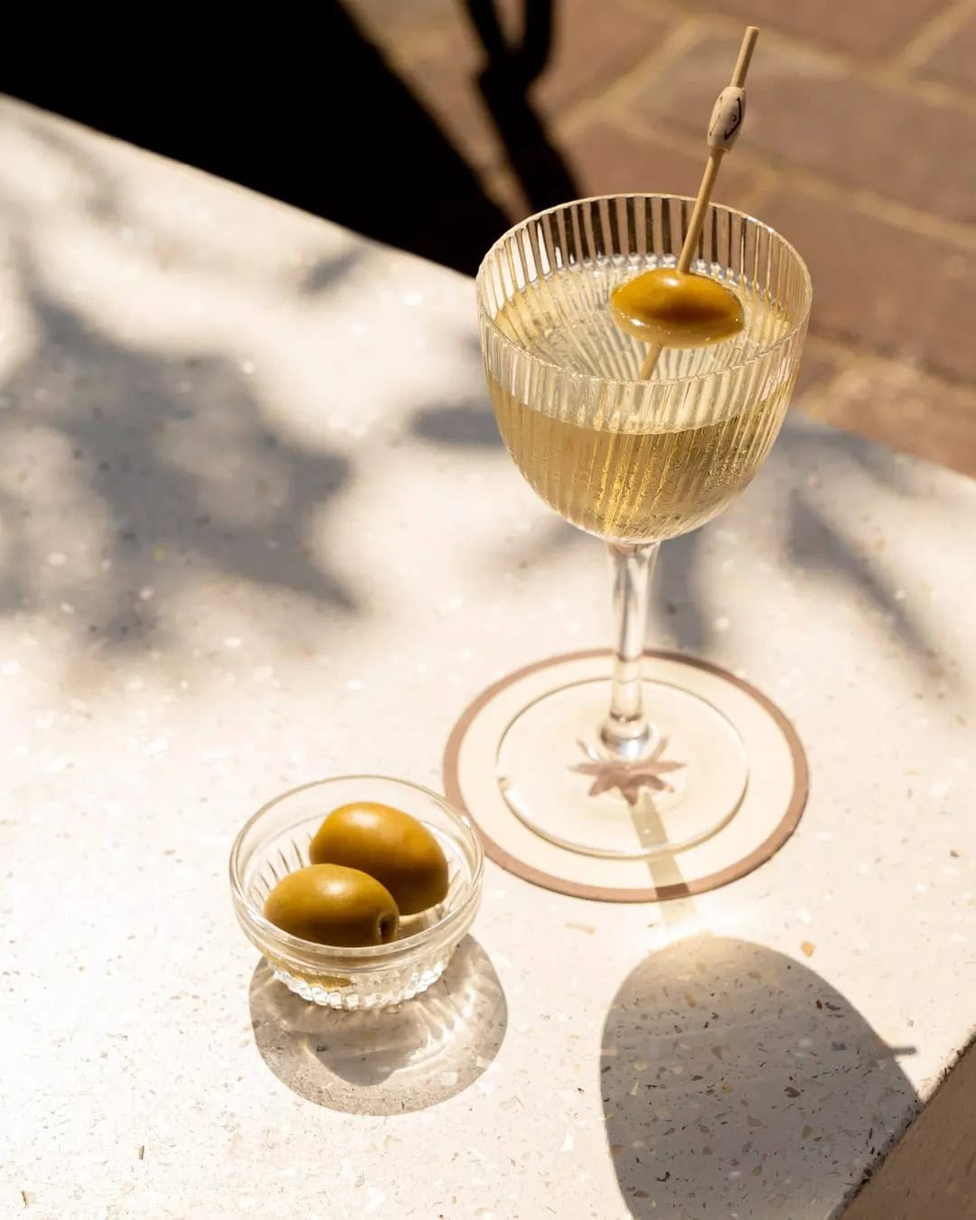 A martini and olives atop a table at beach bar promenade.