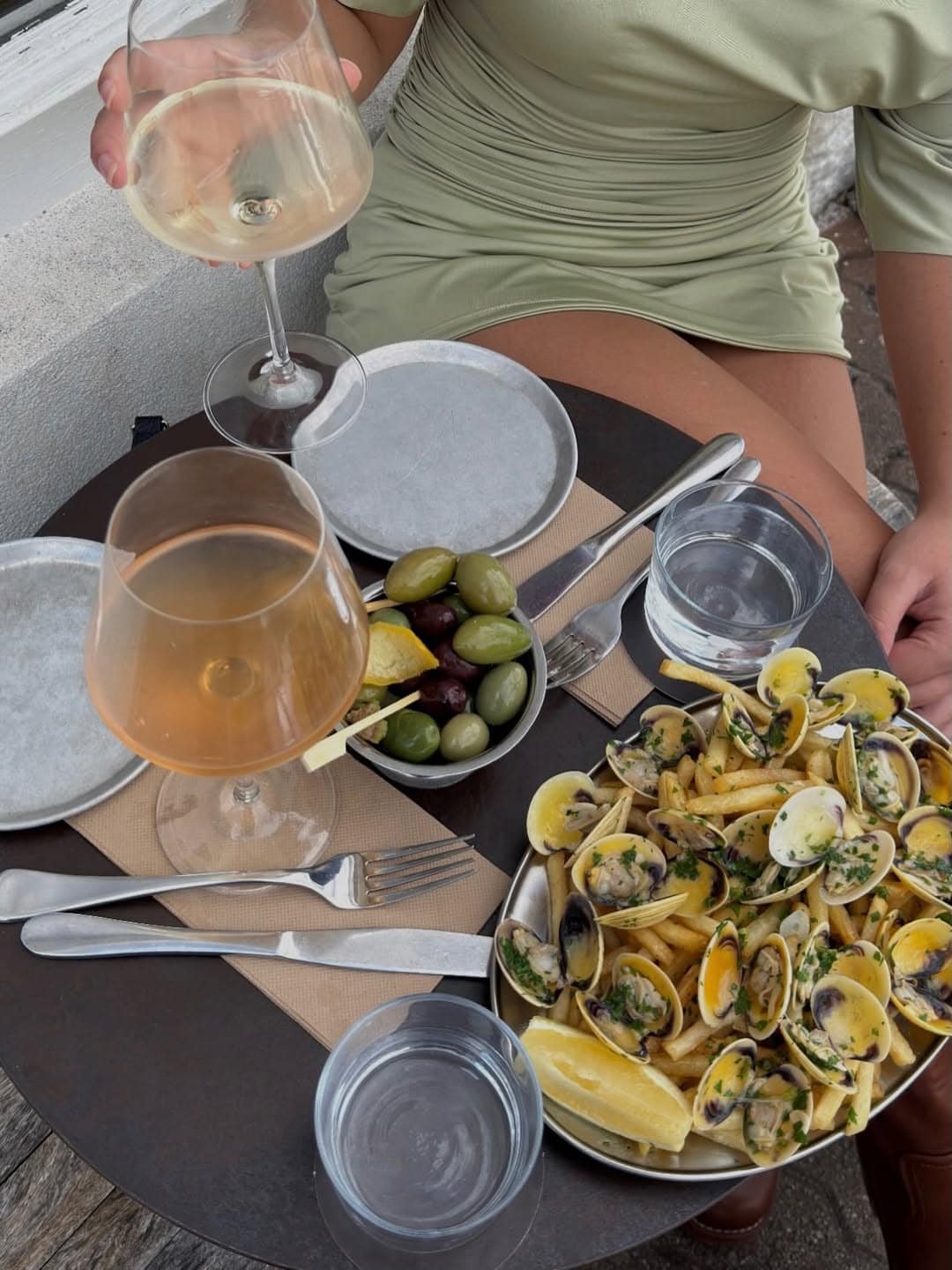 Outdoor table spread with vongole frites olives on skewers and natural wine glasses at Effie's Seaforth Sydney