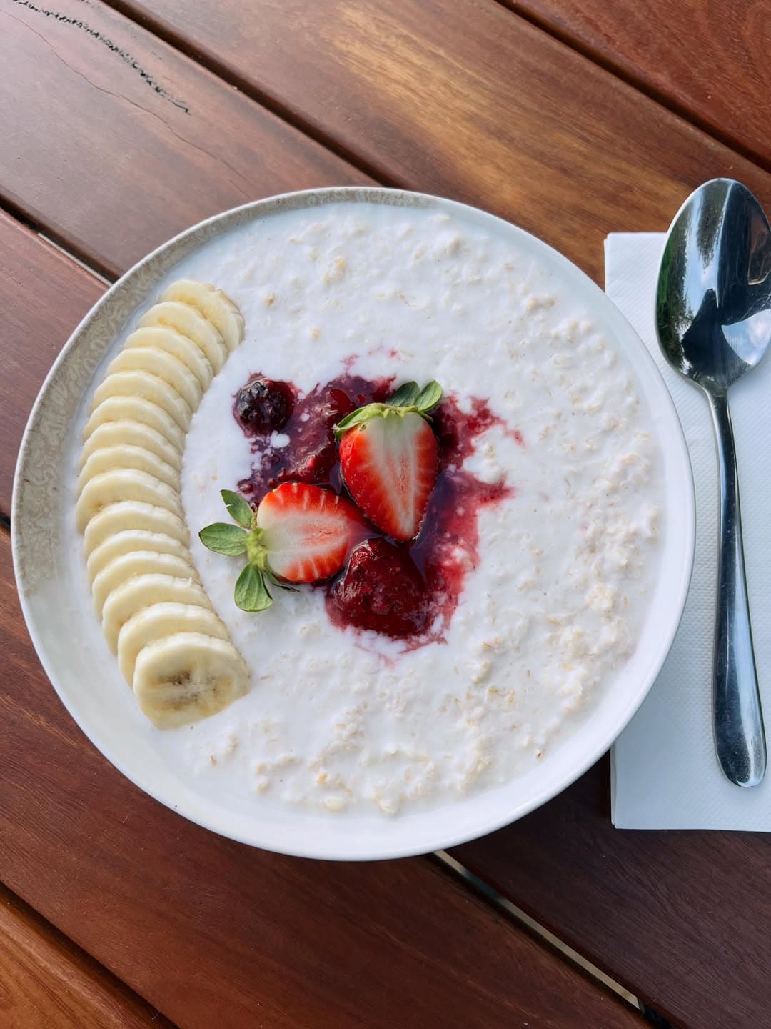 A big bowl of porridge topped with fresh strawberries and banana at gusto on the beach.