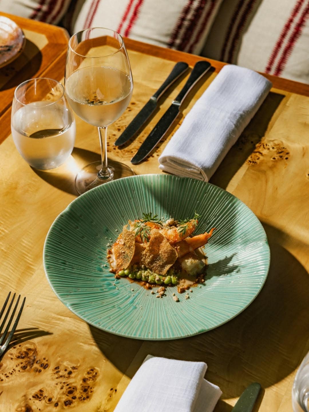 A prawn dish atop an aqua plate, sitting on a wooden table at Sails in Lavender Bay