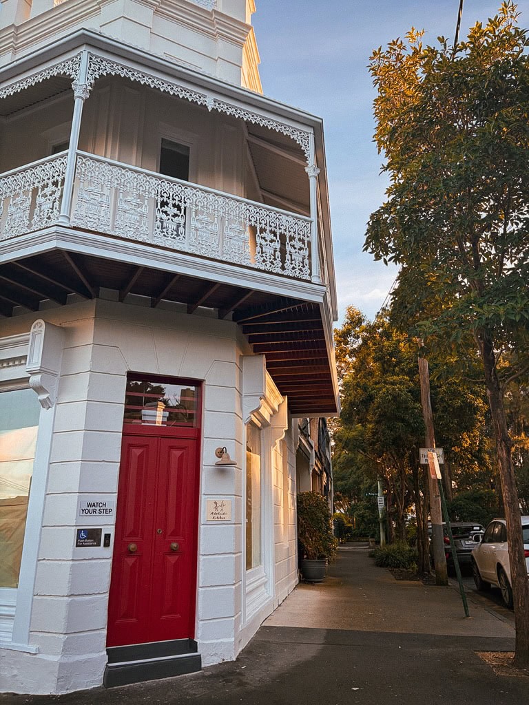 Red door exterior and heritage balcony at Adelaide's Kitchen Paddington Sydney