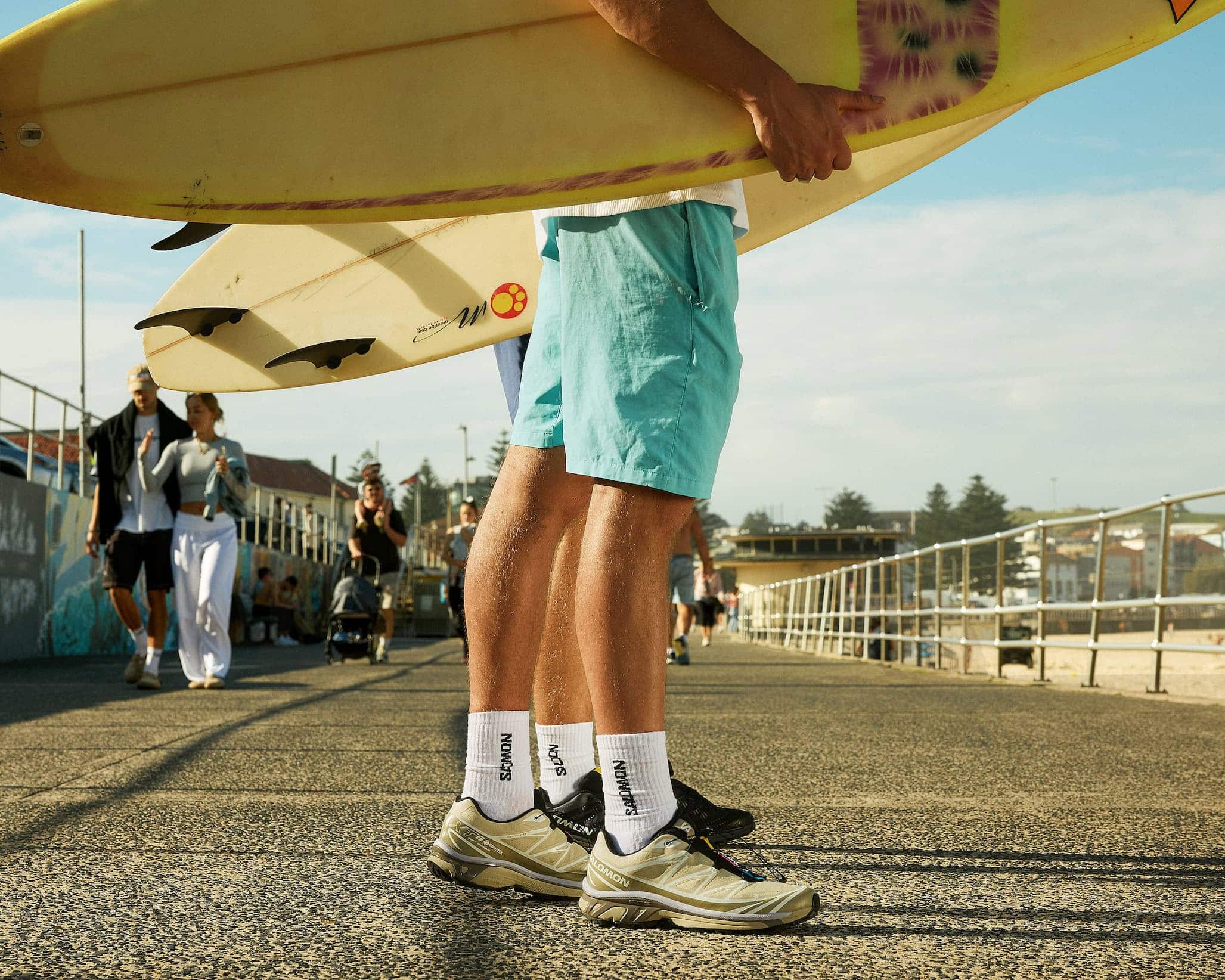 Surfer wearing Salomon sneakers on Bondi Beach boardwalk Sydney