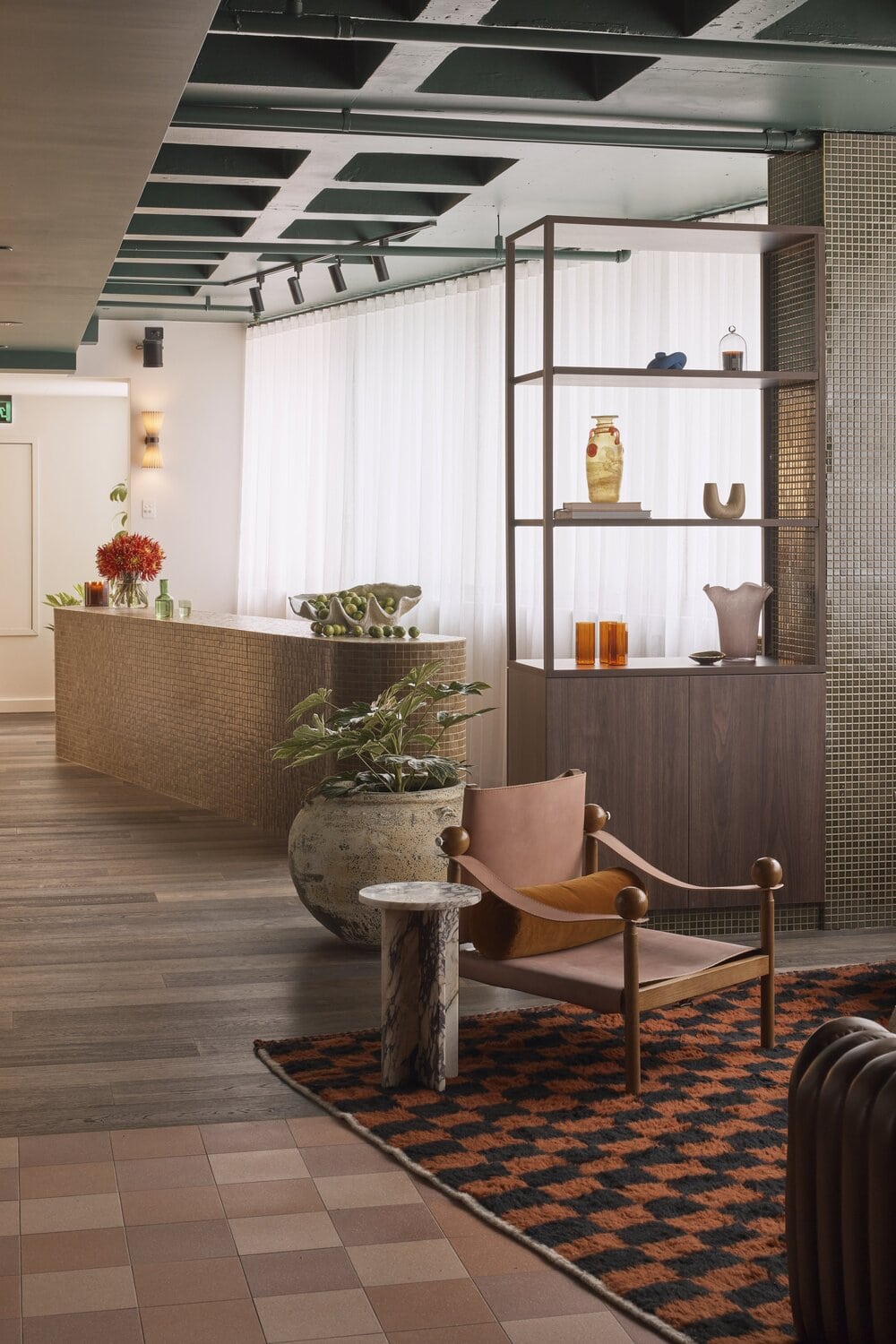 Salon HER reception lobby with curved tile desk leather armchair and open shelving with decorative objects Darlinghurst Sydney