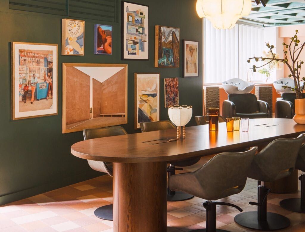 Salon HER styling floor with dark green gallery wall wooden oval table and hair washing basins Darlinghurst Sydney
