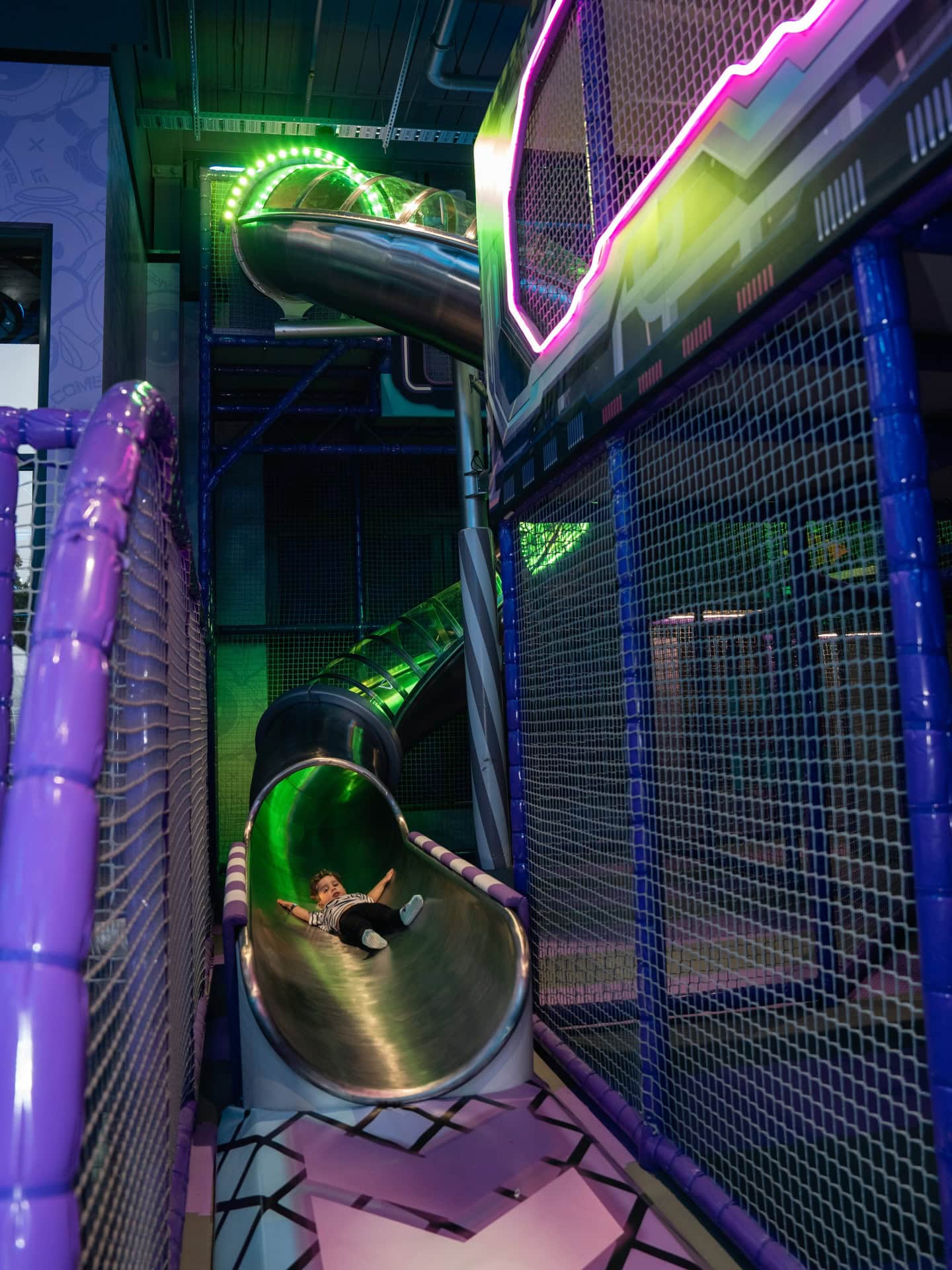 A child coming down the slide at the neon area 51.
