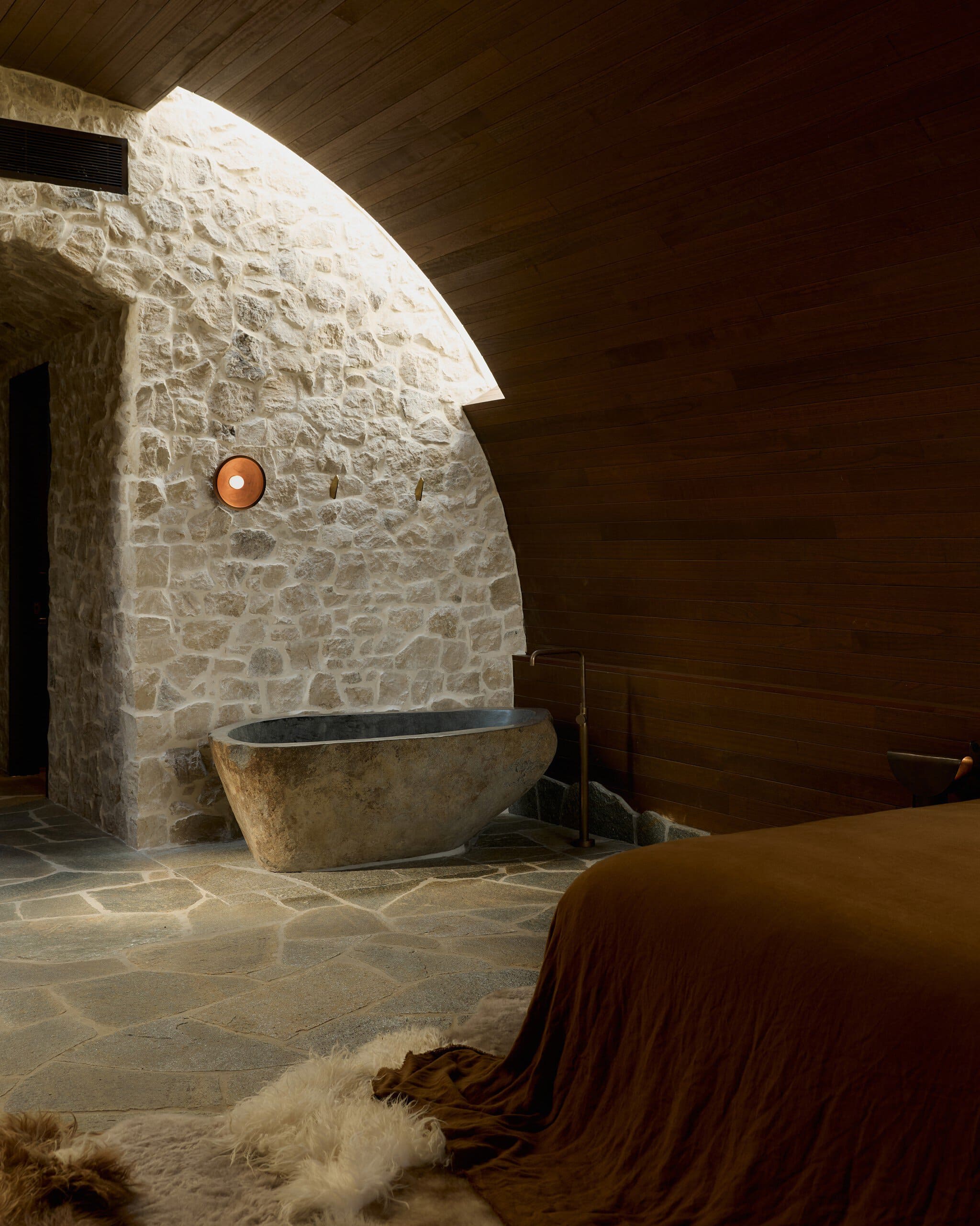 Chic bedroom with stone wall and bathtub in Byron Bay.