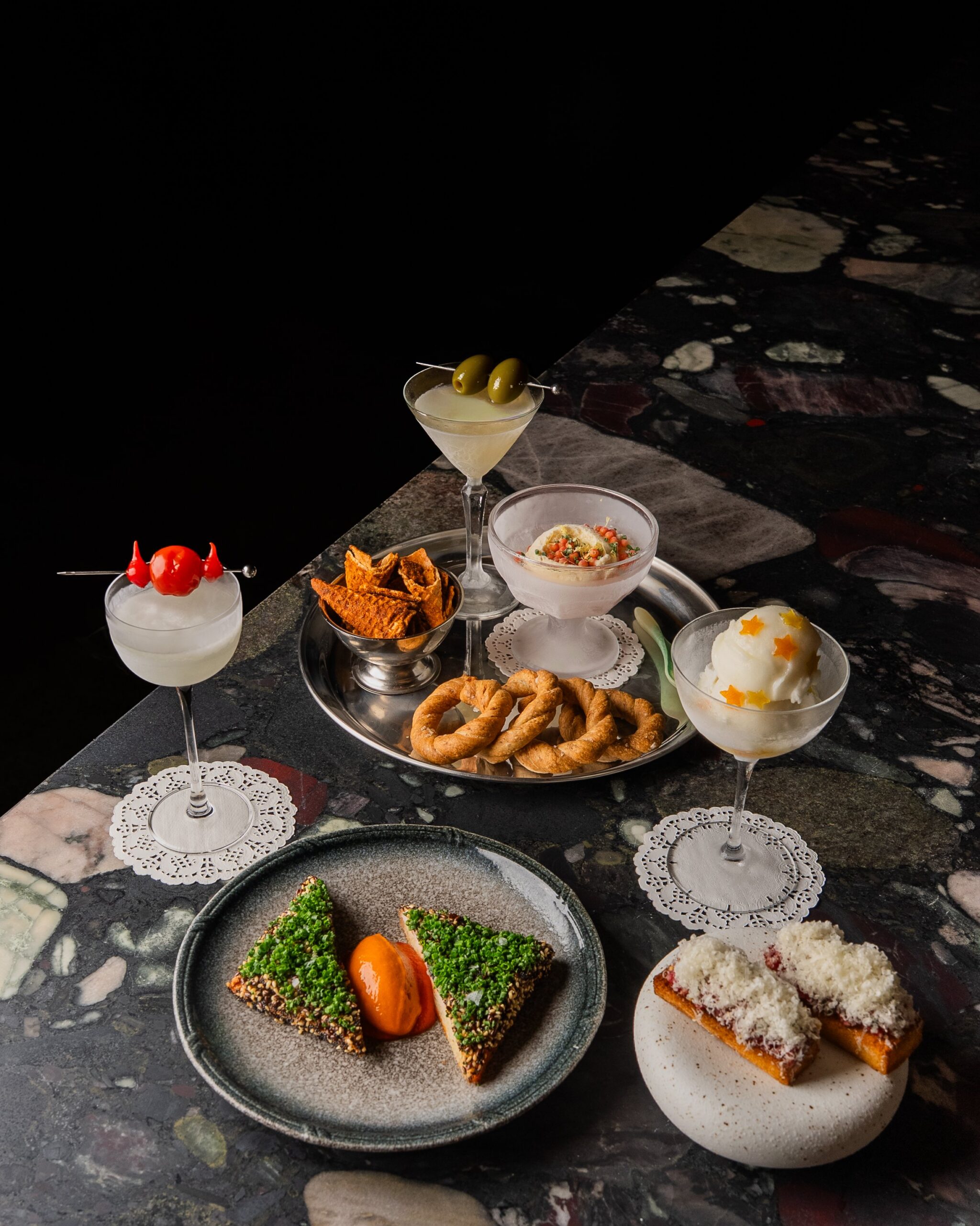Three martini dinner spread with dirty martini tomatini sorbetini prawn toast snack tray and beef tartare on brioche on marble bar at Erin Marrickville Sydney