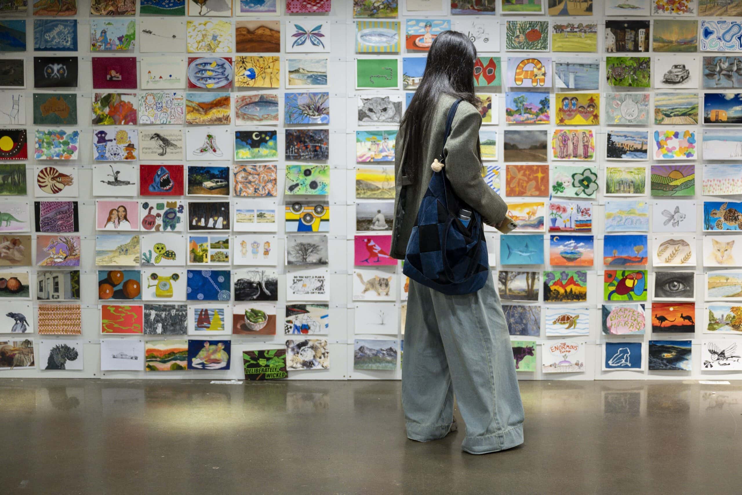 Visitor viewing wall of A5 artworks at Incognito Art Show Carriageworks Sydney