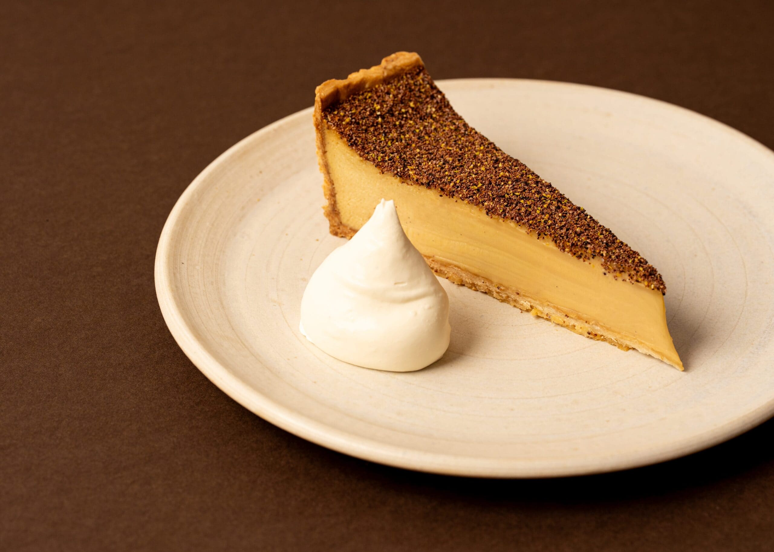 Slice of wattleseed custard tart with cream quenelle at Arthur Surry Hills Sydney