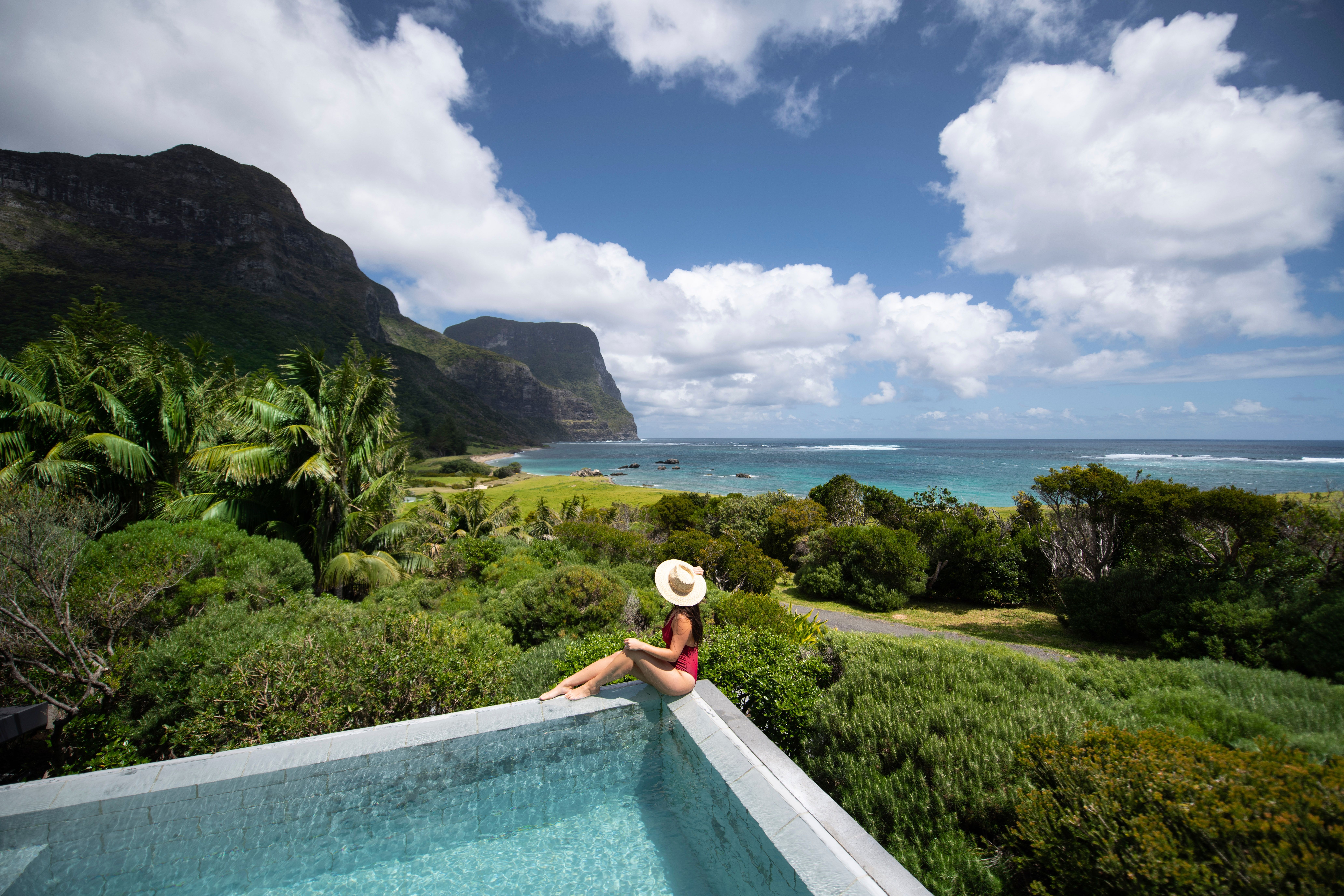 Woman relaxing by the pool at Capella Lodge, Lord Howe Island.