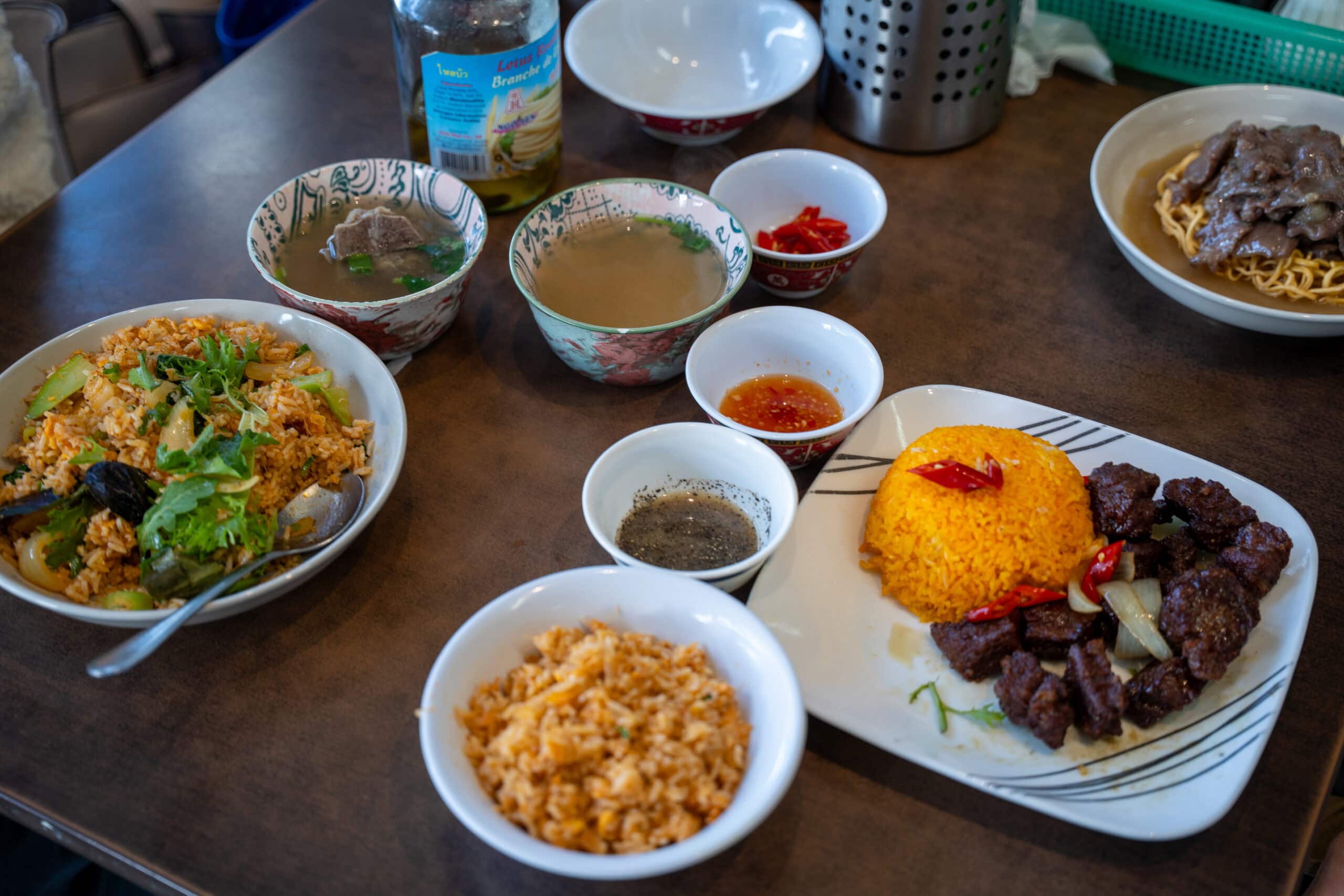 Table set with Cambodian rice dishes, soup, noodles and dipping sauces.