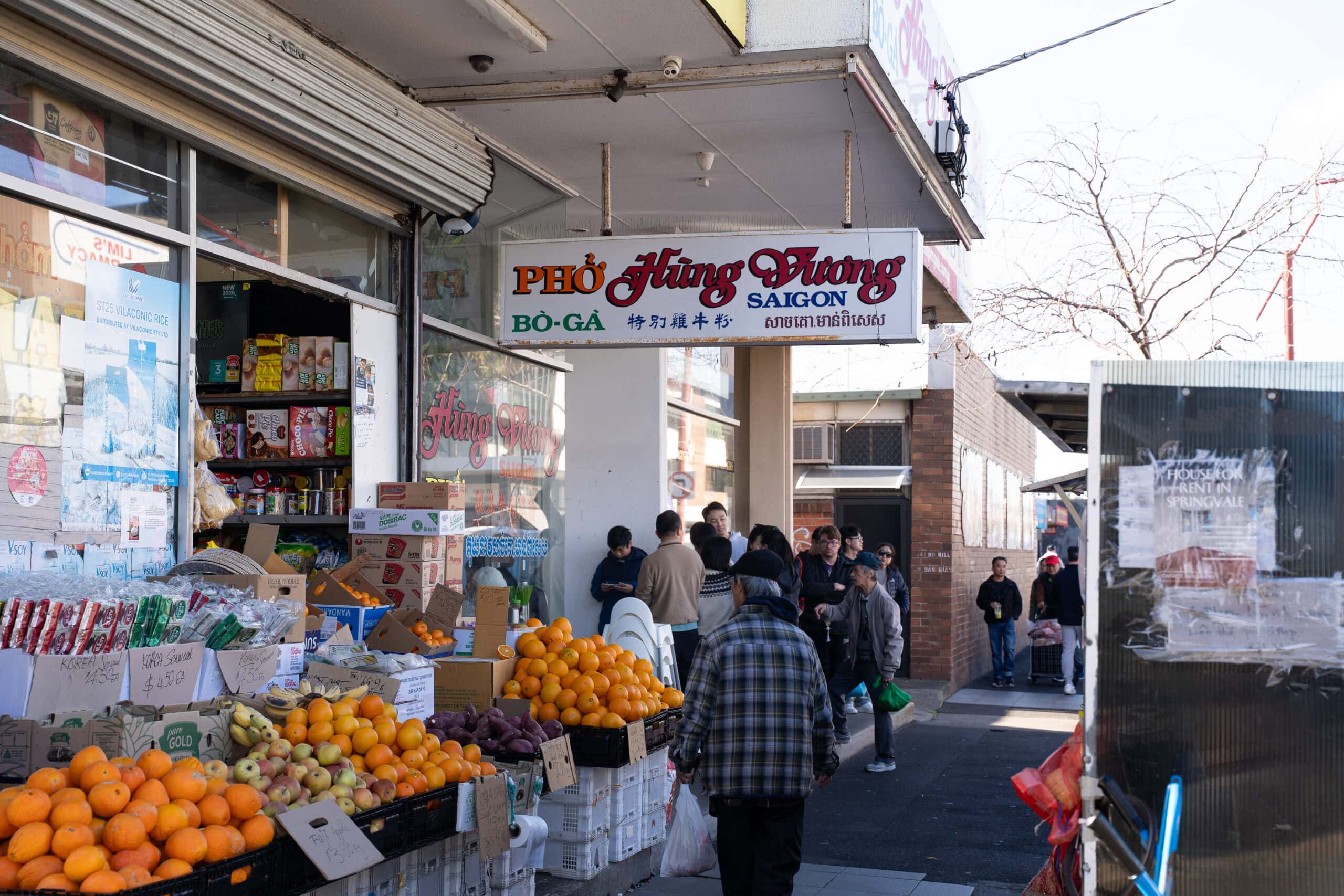 Exterior of Pho Hung Vuong Saigon with shoppers and fresh produce outside.