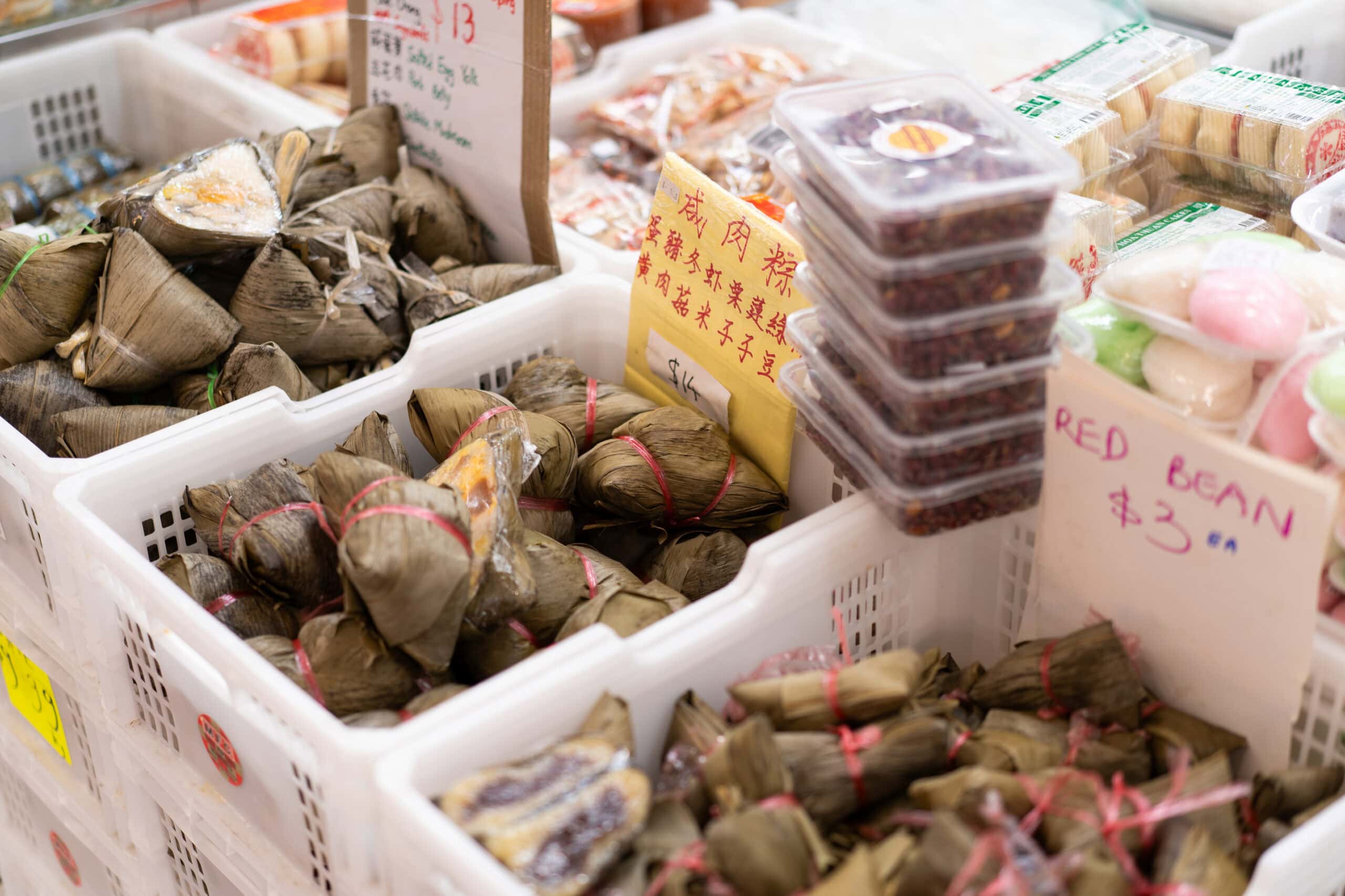 Leaf-wrapped rice dumplings and traditional Asian snacks on display at Golden Age Bread & Cake.