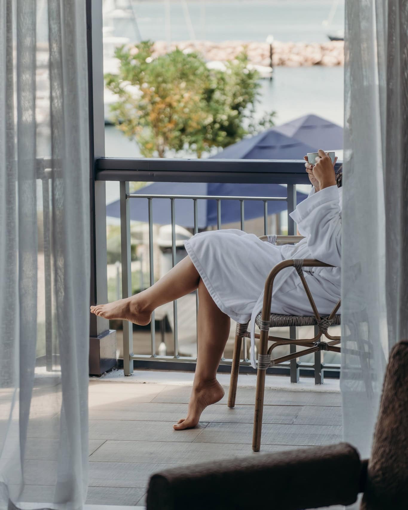 Someone relaxing in a white robe on the balcony of Anchorage Resort & Spa in Port Stephens.